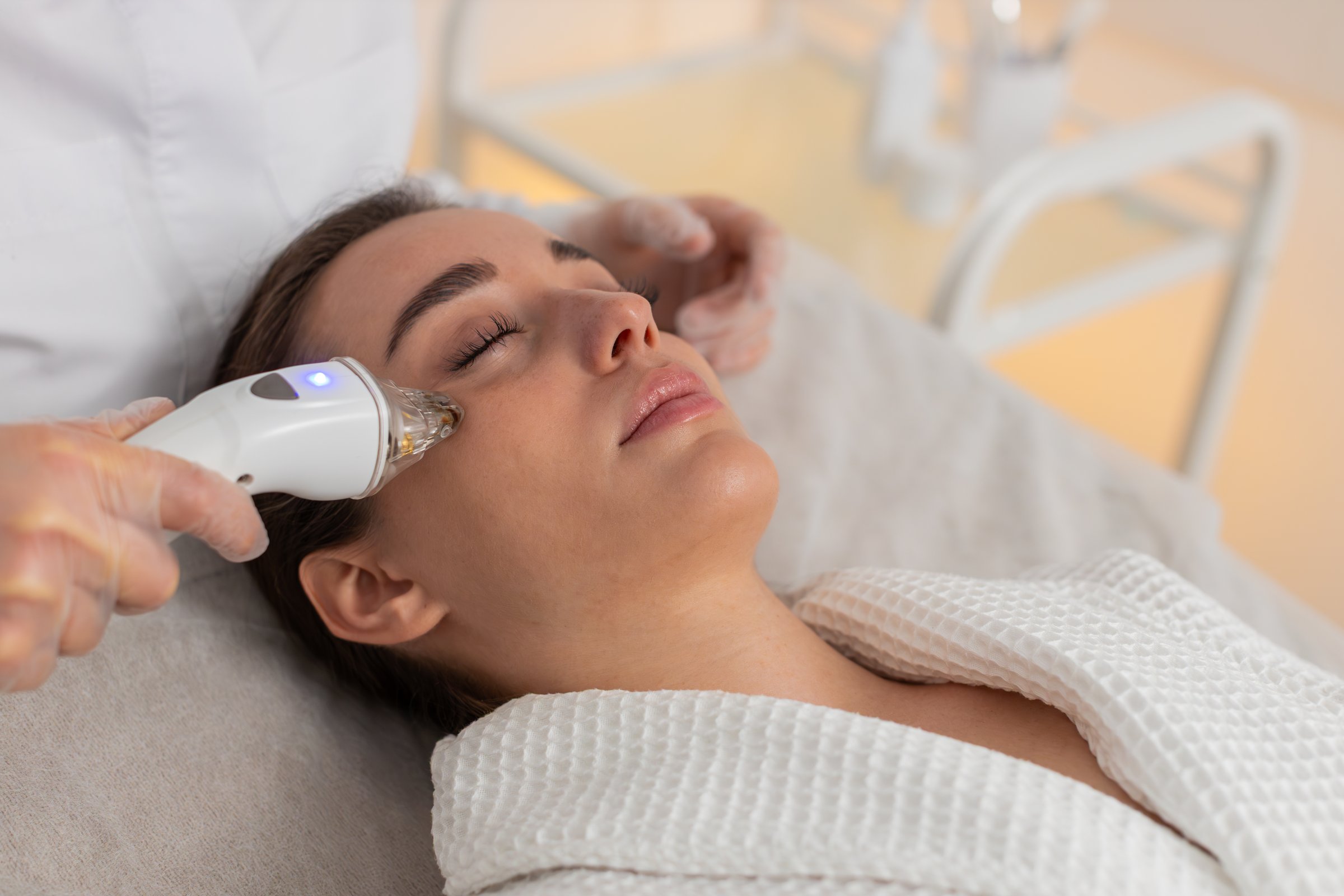 Caucasian woman girl receives RF therapy under eyes in cosmetology clinic. Cosmetologist uses professional device to tighten skin, stimulate collagen, improve elasticity and reduce wrinkles gently