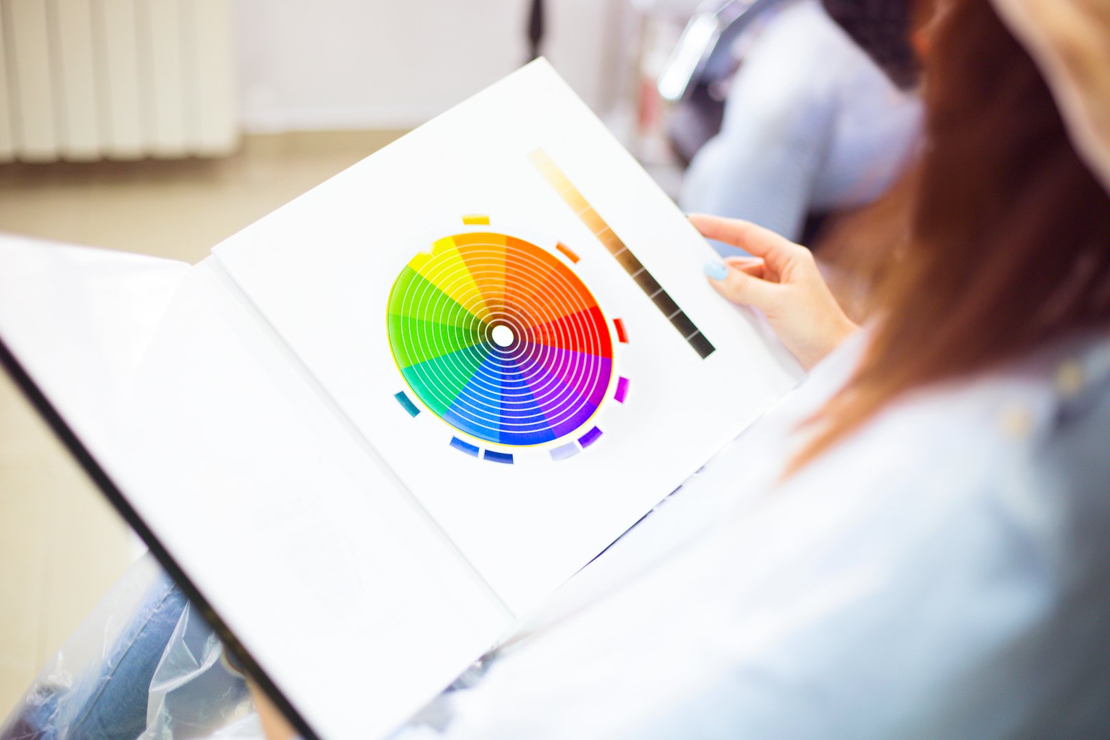 Close up of a female client examining hair color chart at the hairdressing studio coloring dyeing variety changing women hair care. Feminine beauty concept.