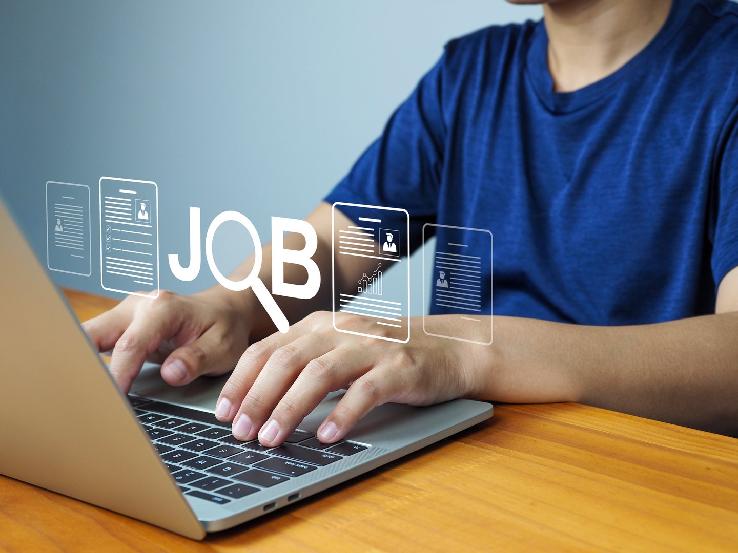 Job search concept with person typing on laptop keyboard, digital icons of resume and magnifying glass over wooden table, online recruitment and employment opportunity