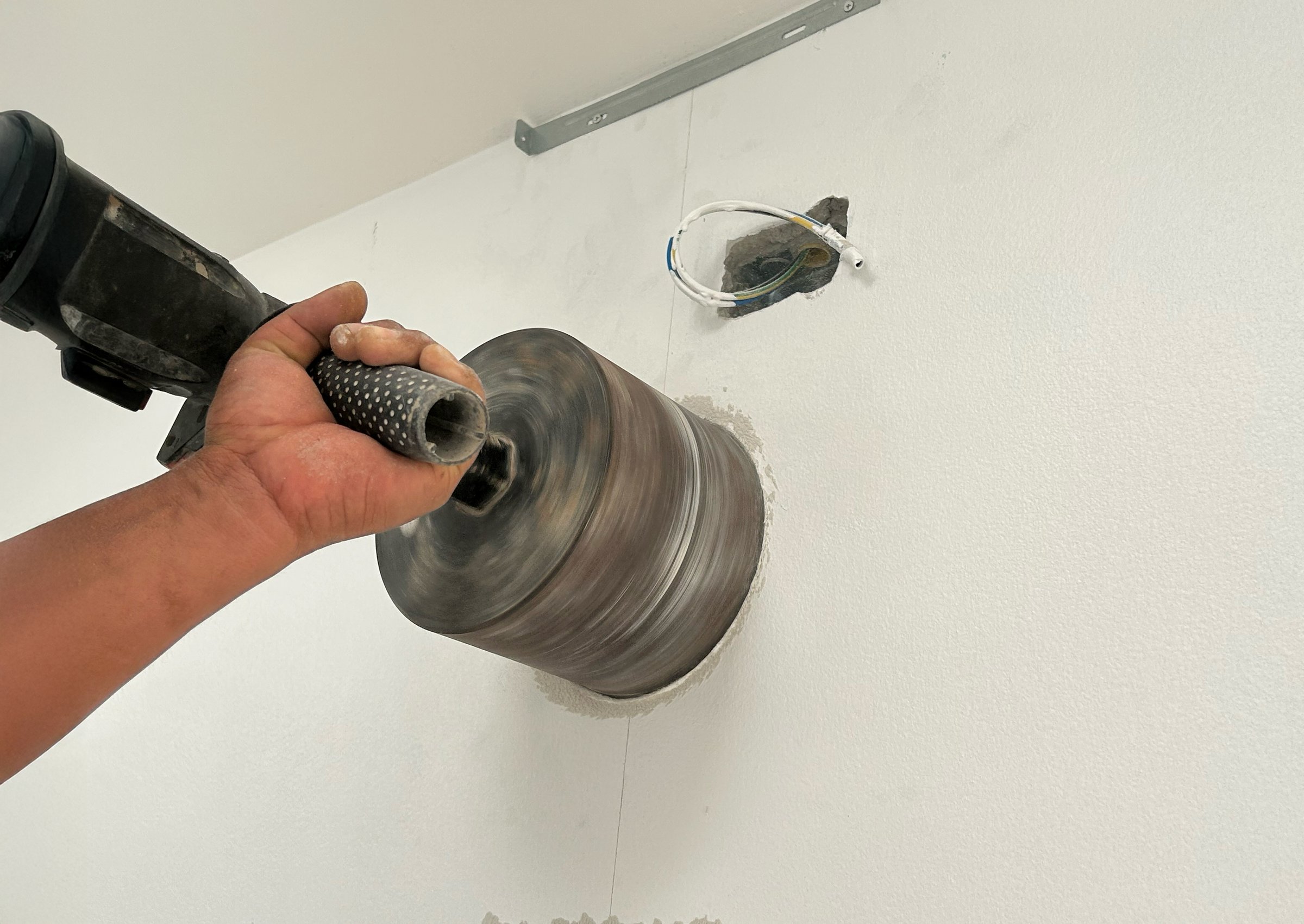 Worker Drilling kitchen wall to mounted hood air duct.