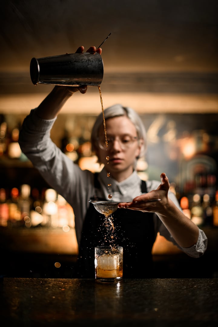 Female bartender pouring a cocktail