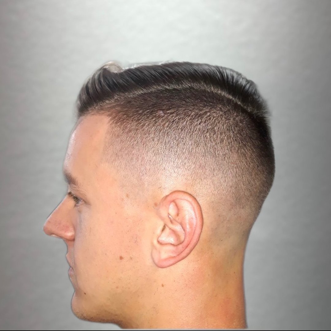 Side view of a man with a high fade haircut, showing short, neatly trimmed hair on the sides and slightly longer on top.