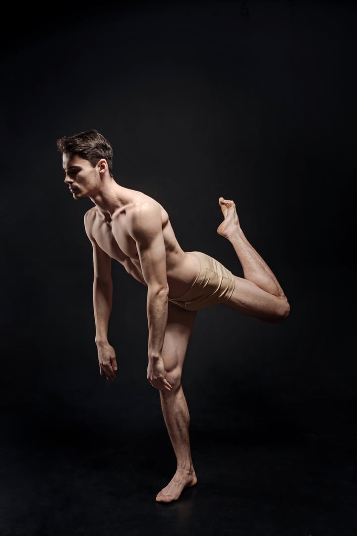 Perfection of every motion. Young talented handsome ballet dancer performing isolated in black background and demonstrating his skills while having a rehearsal