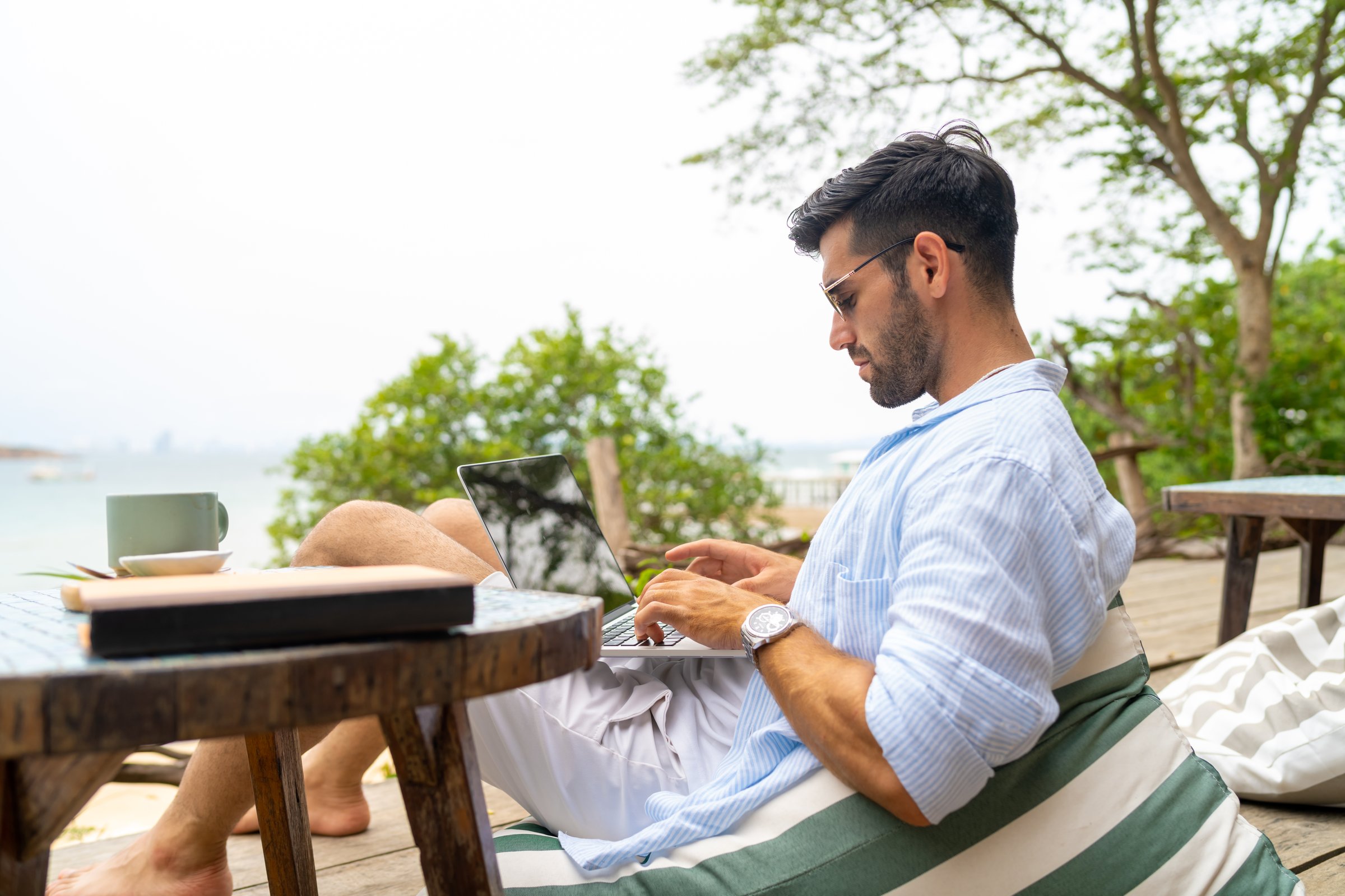 Caucasian businessman remote working online corporate business financial on laptop computer at beach cafe. People enjoy outdoor lifestyle travel tropical island on summer beach holiday vacation.