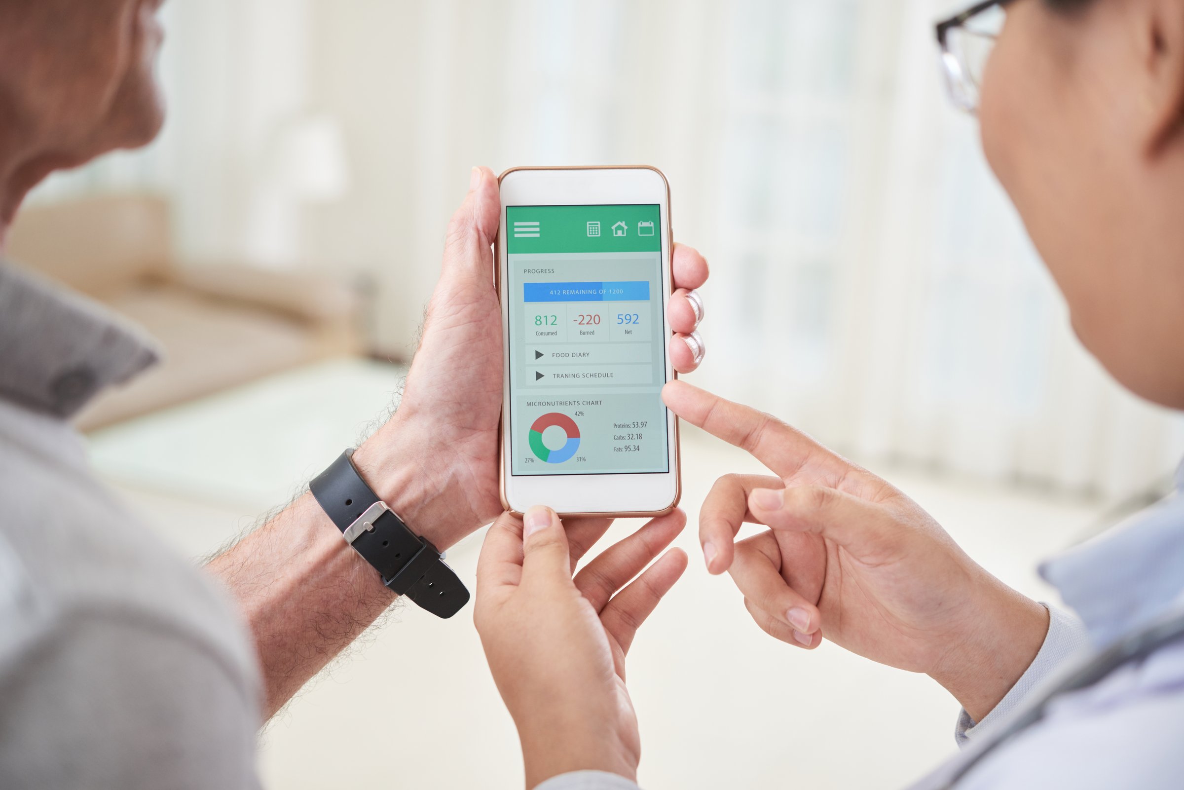 Crop back view of senior man and female doctor watching contemporary health tracking application on smartphone