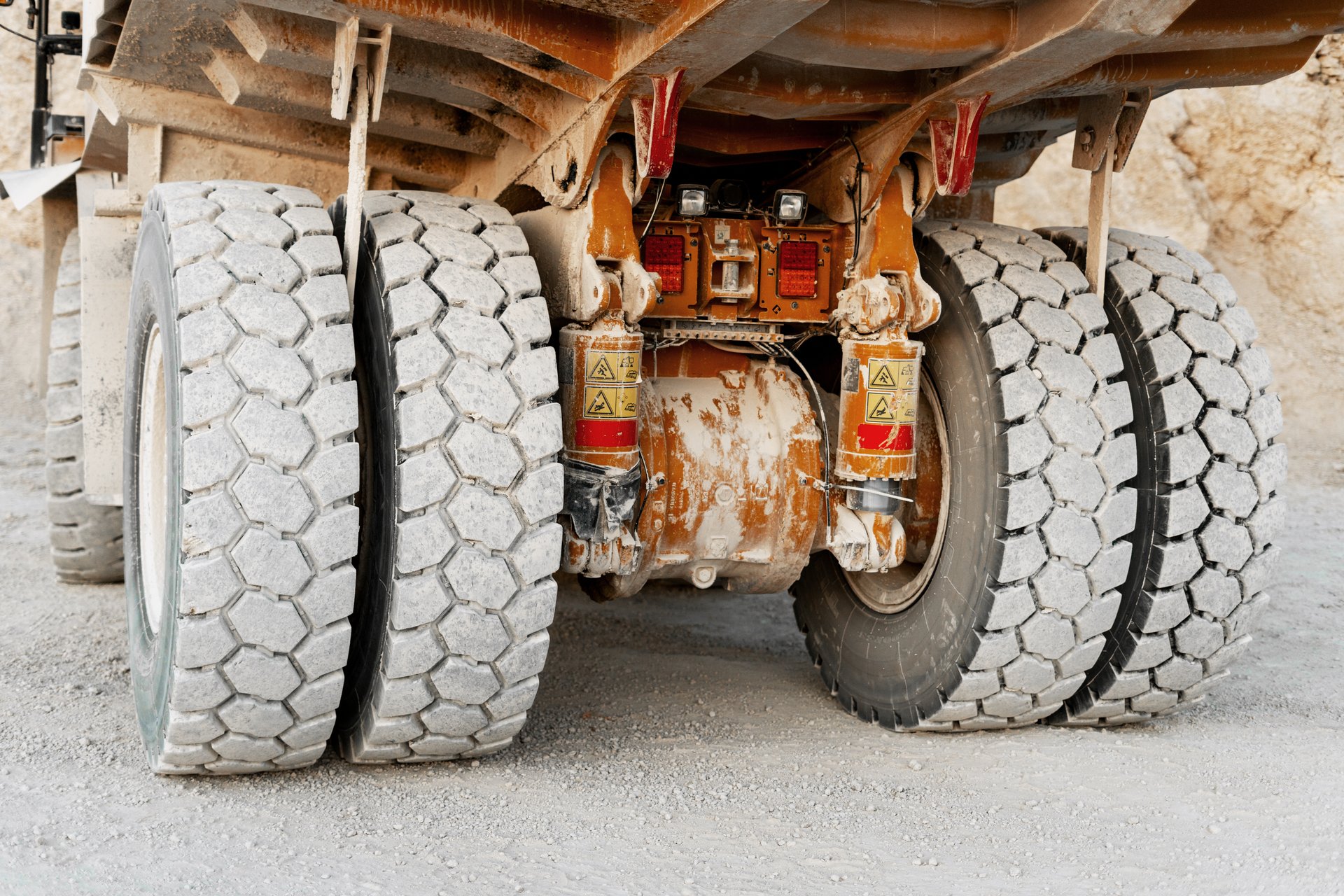 Close-up view of heavy-duty mining truck's rear wheels on gravel road