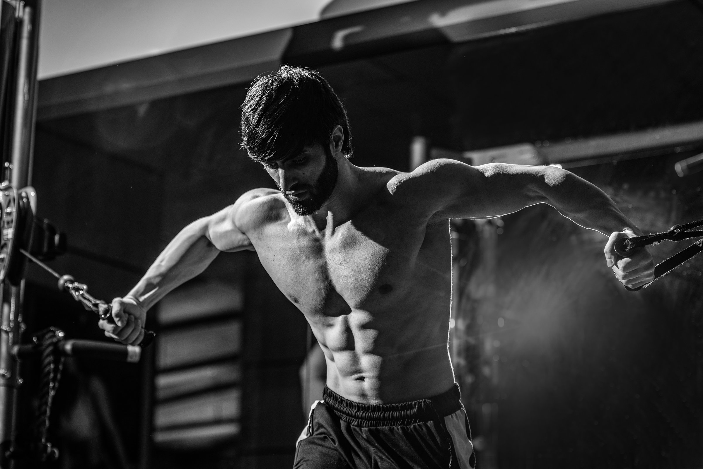 A grayscale shot of a fit athletic muscular Caucasian man working out at the gym