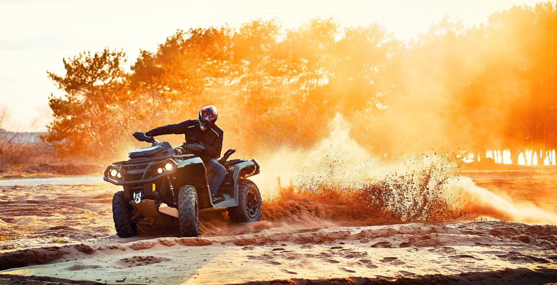 Teen riding ATV in sand dunes making a turn in the sand