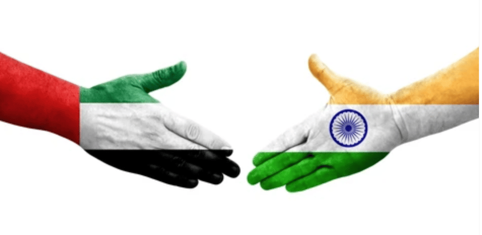 Two hands painted with UAE and India flags reaching to shake hands, symbolizing cooperation or partnership.