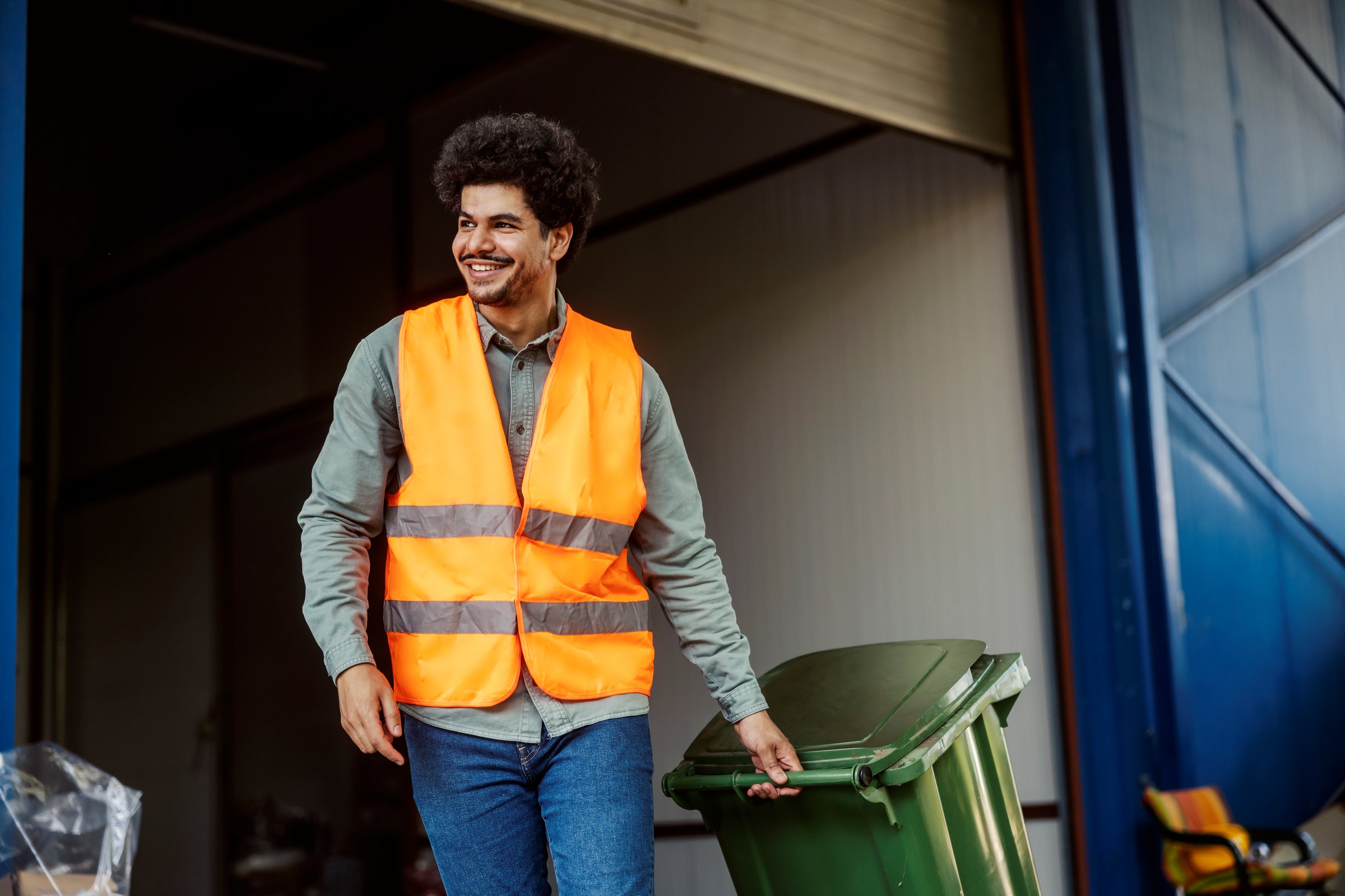 Diverse storage manual worker with trashcan taking out garbage.