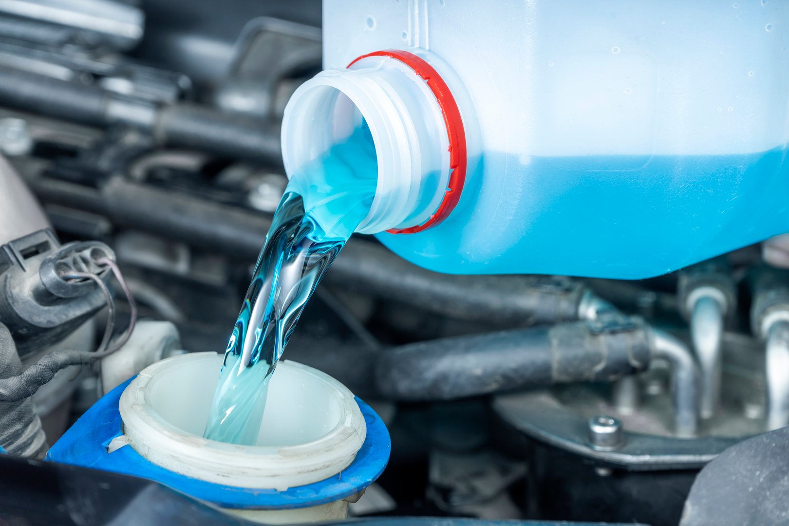 Close-up of pouring windshield wiper fluid from bottle to reservoir. Checks levels and periodic maintenance of cars.