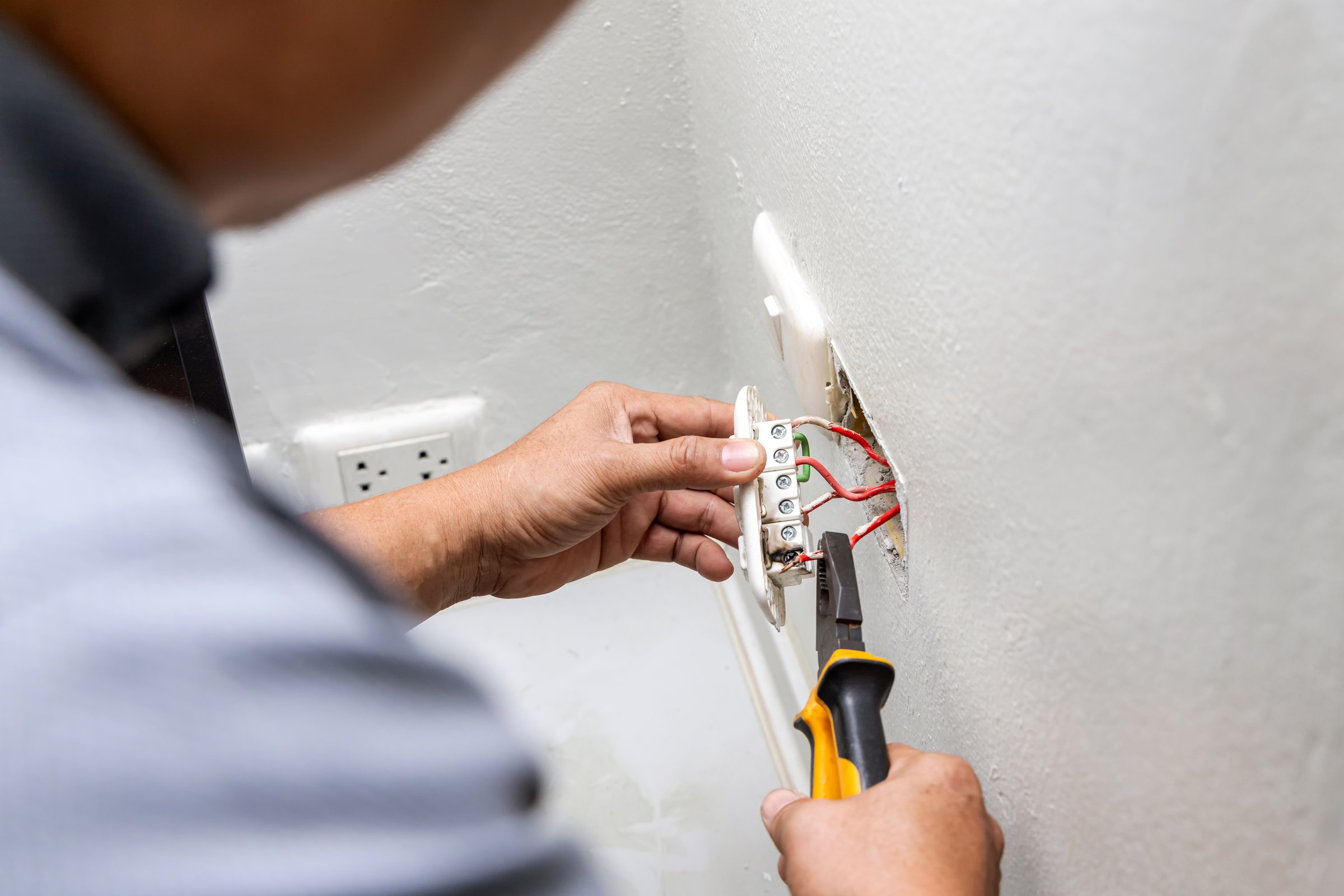 Electrician holding electric outlet plug for repair or maintenance and fixing in office room. Dangerous of electric spark from short circuits and fire in house.