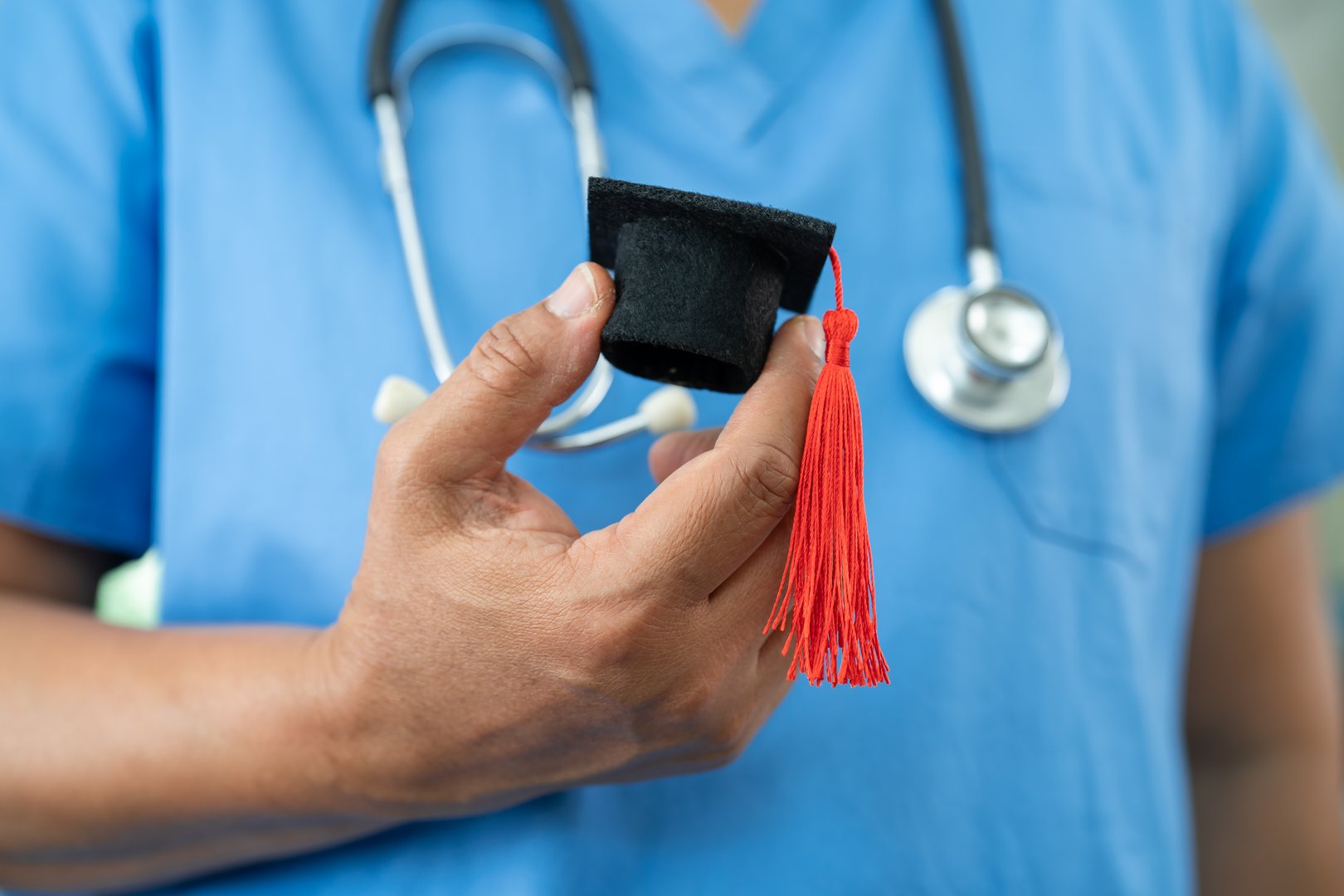 Asian doctor holding graduation gap hat, education medicine.