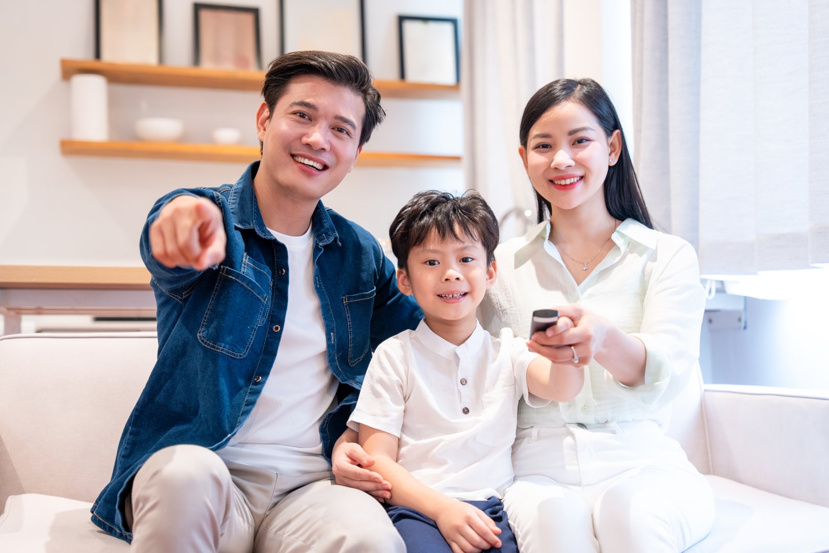 The smiling family enjoys a cozy time at home Father points out mother holds the remote control