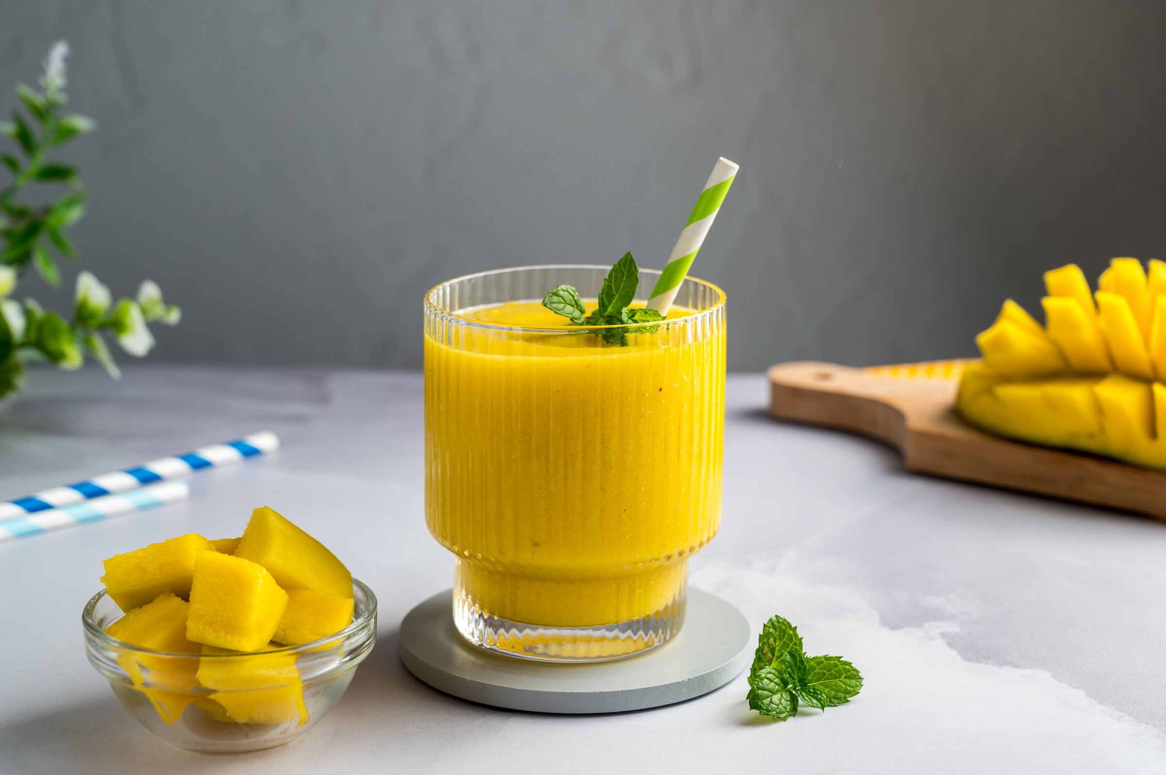 Mango banana smoothie in a glass with fresh fruit and mint