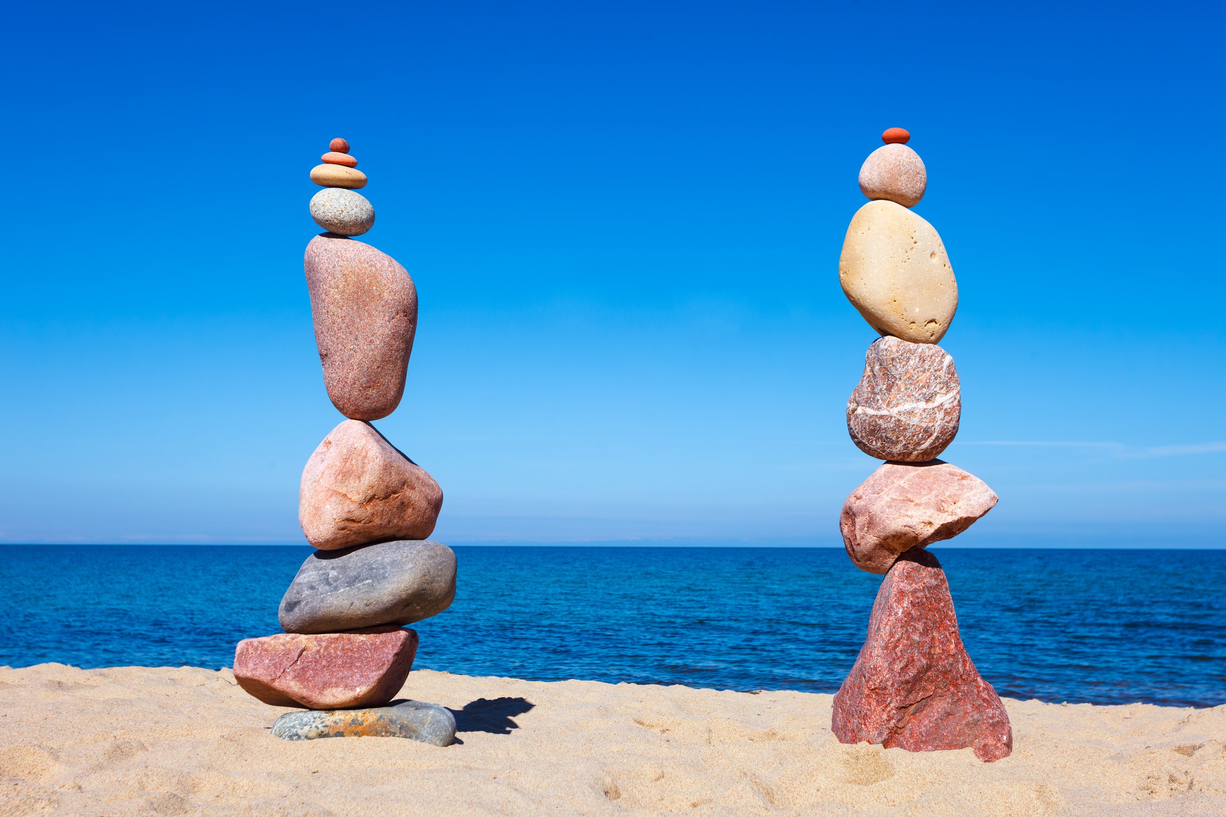 Two high Rock zen pyramids of colorful pebbles on a beach on the background of the sea. Concept of Life balance, harmony and meditation
