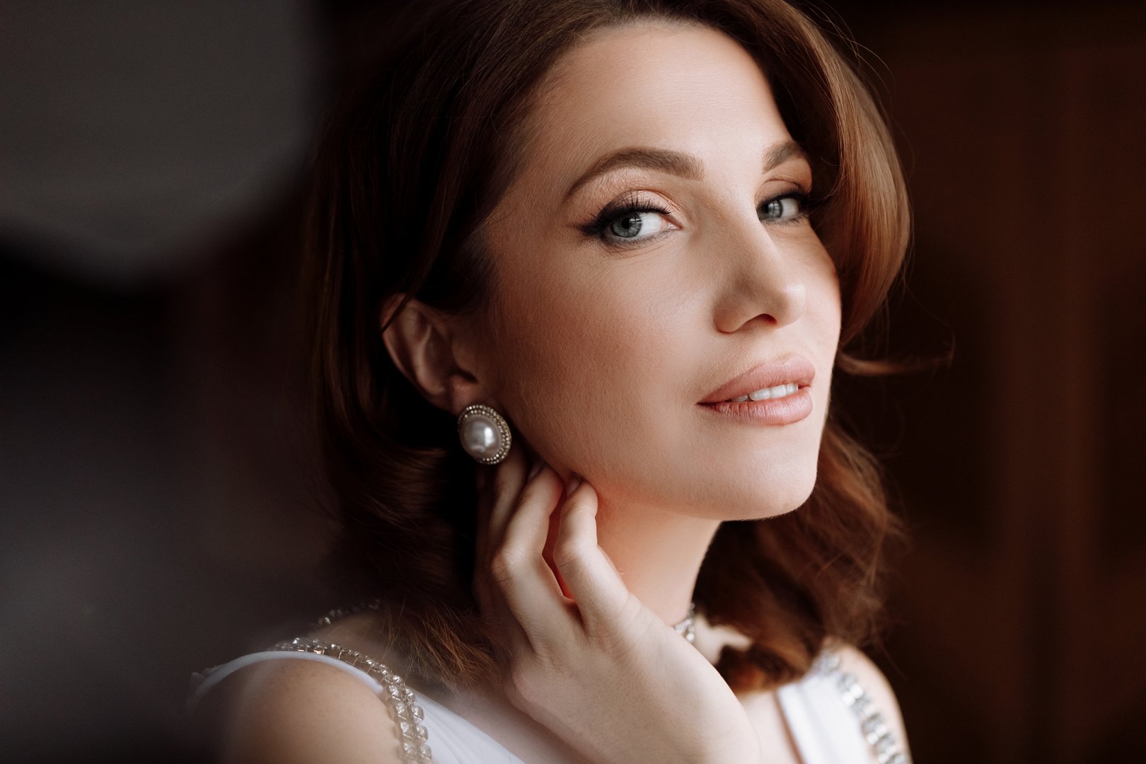 beauty concept. portrait of a beautiful young showy brunette woman with bright pin-up make-up and hairstyle. girl in luxury dress and earrings pearls and looking in camera. international women's day.