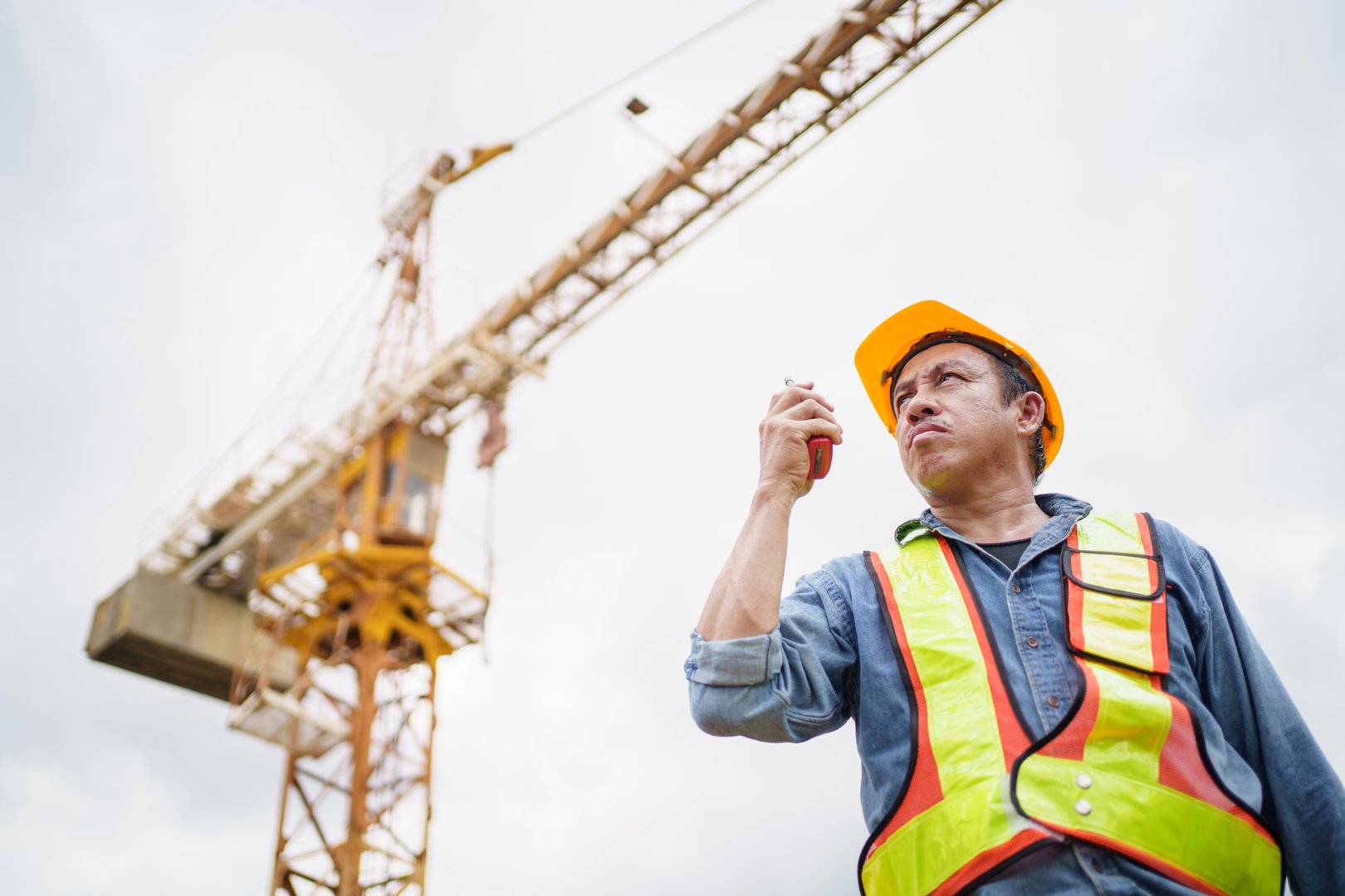 Senior caucasian white industrial engineer is performing inspection a heavy machines and computer systems in the factory. Senior engineer checks manufacturing production line.