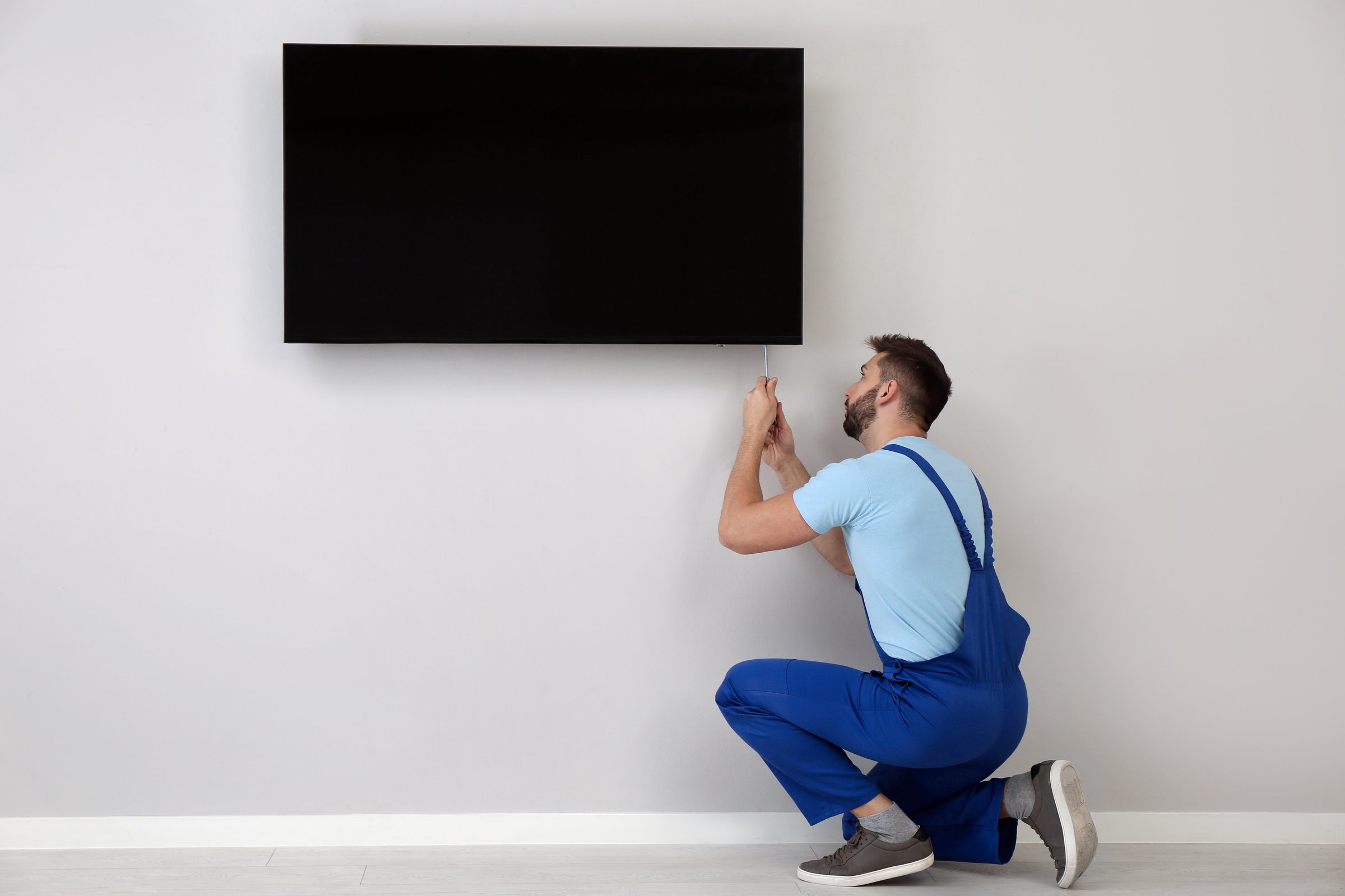 Professional technician installing TV on wall