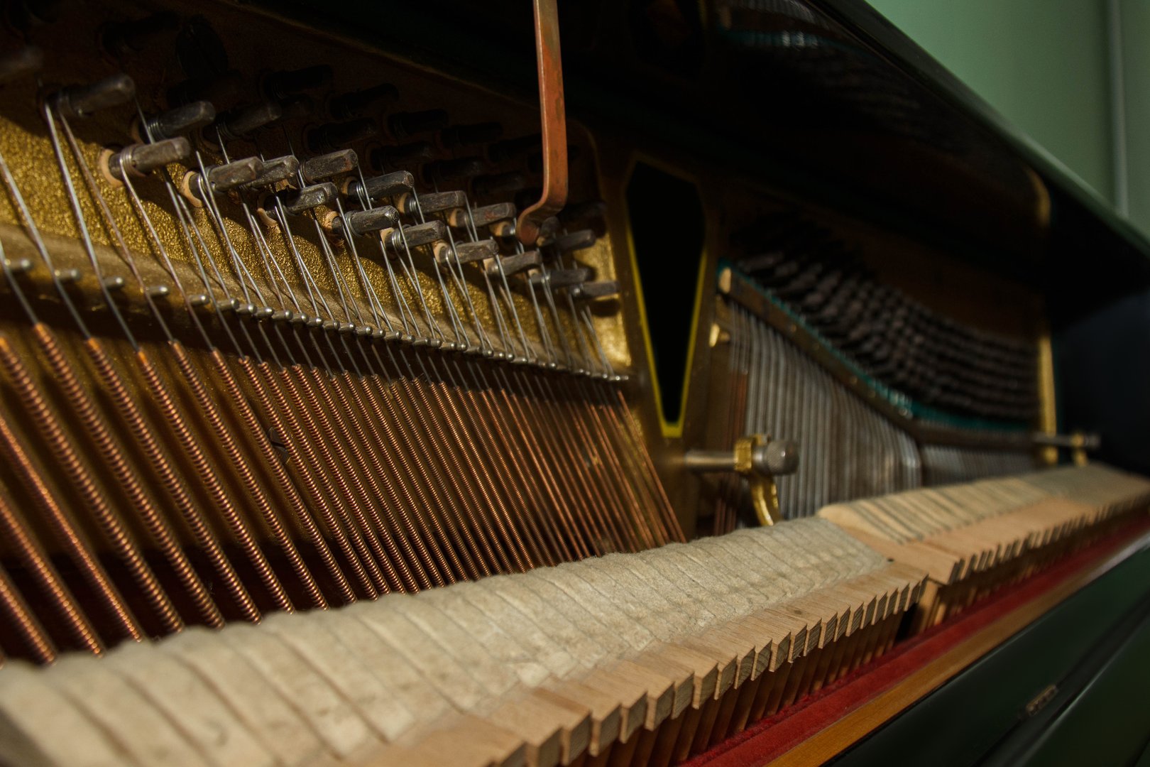 Repair of a stringed musical instrument. The interior of a piano with brass metal strings and a wooden mallet. Old fashioned musical instrument for performing music