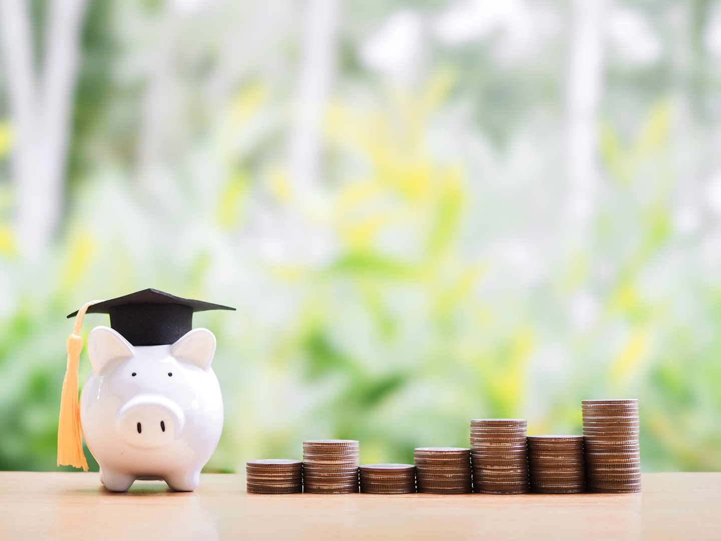 Piggy bank with graduation hat and stack of coins. The concept of saving money for education, student loan, scholarship, tuition fees in the future
