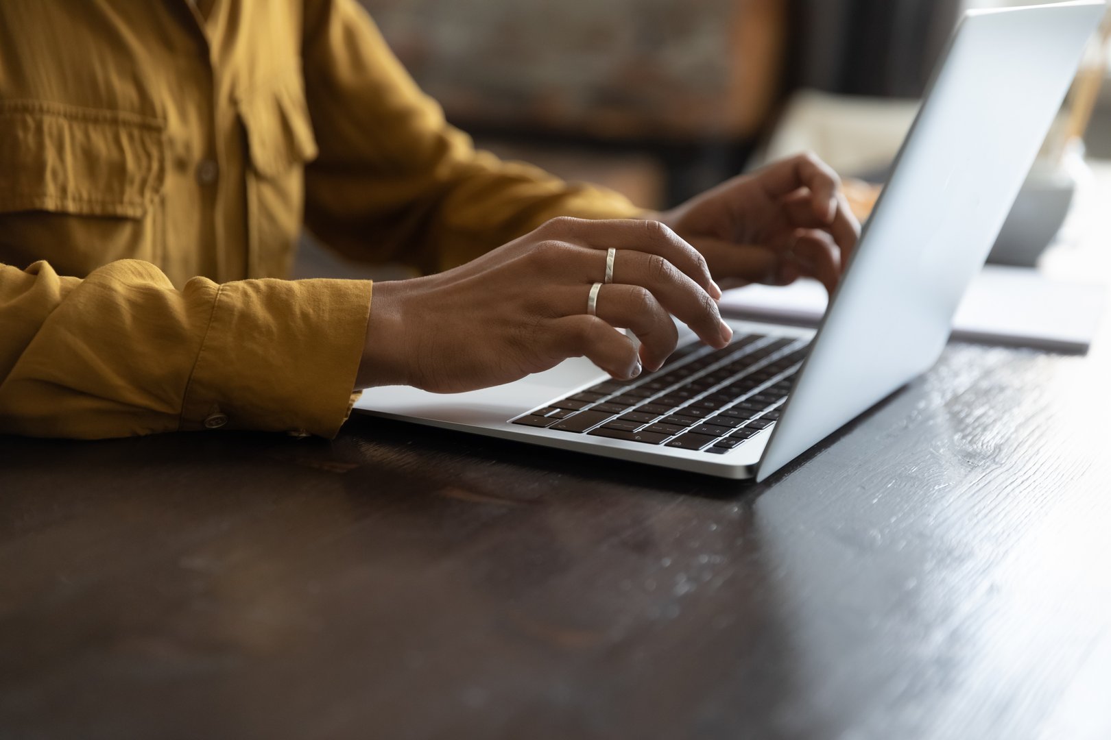 African female employee working at laptop, typing on keyboard. Woman hands close up. Businesswoman in casual, professional working at table, using online app, chatting, writing article. Cropped shot