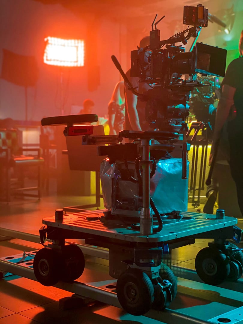 movie camera on the dolly in the backlight from the cinema light, the rays of the sun in a smoky room. cinema set atmosphere