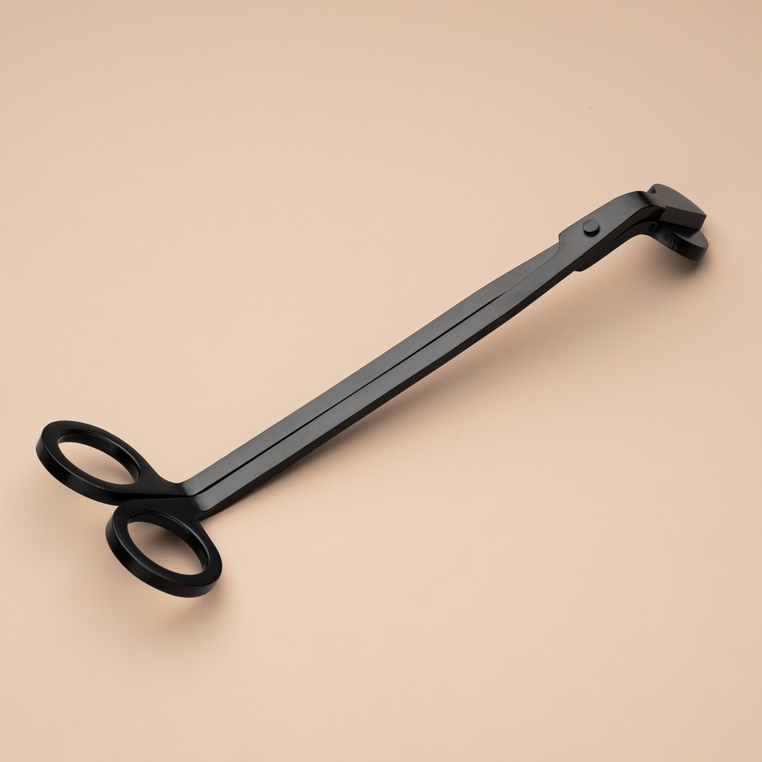 Black candle wick trimmer on a beige background. Stainless steel candle snuffer accessory set. Equipment for scented candles for home use. An accessory for safe home use of aroma candles.