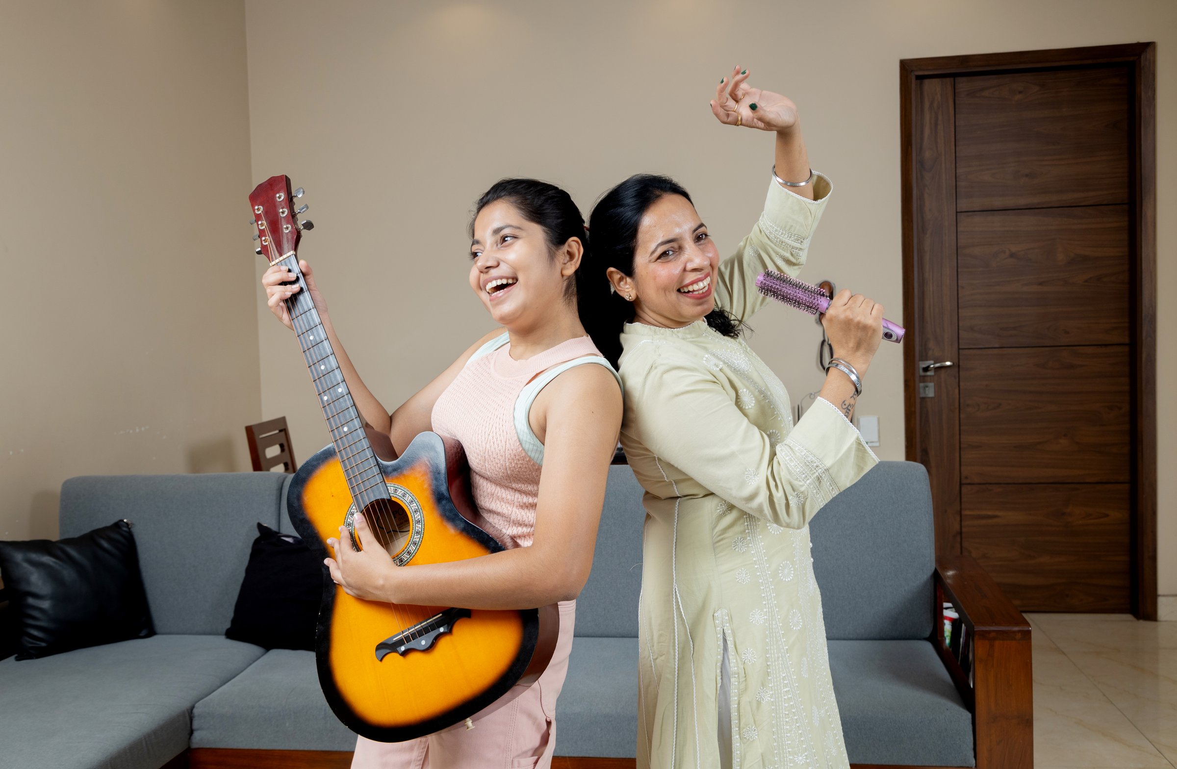Indian Mother singing and Teen daughter playing guitar together , Mother and Daughter singing and dancing at home candid moments