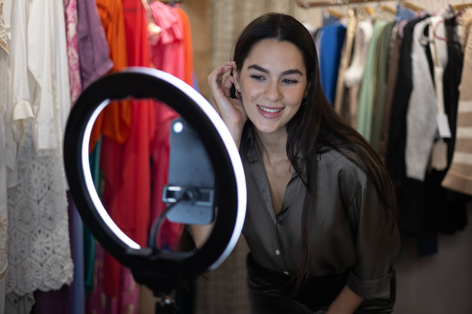 Fashion blogger using smartphone and ring light to create content in a clothing store