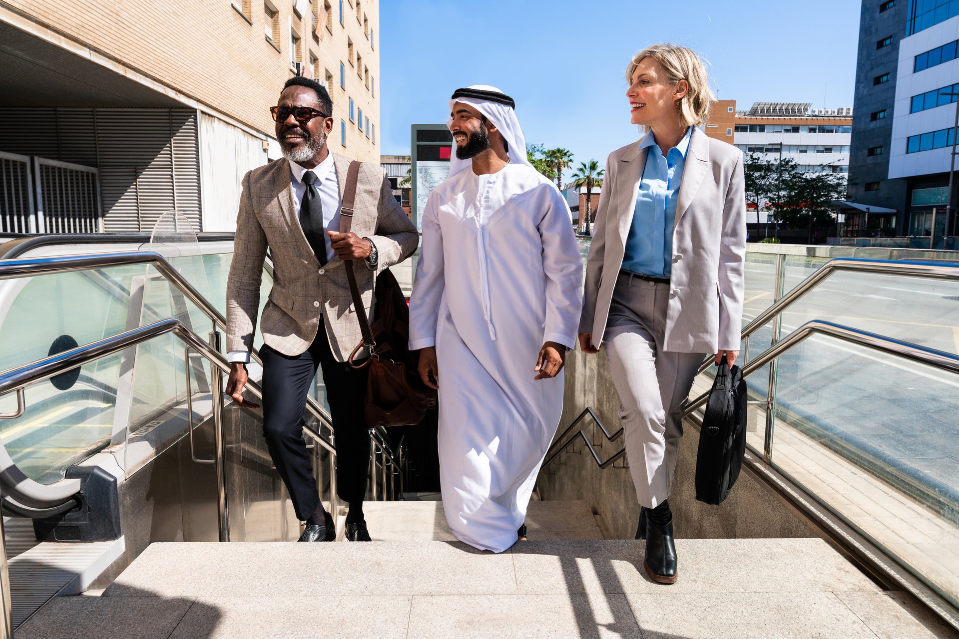 Group of multiethnic business people meeting an emirati businessman - International corporate business team bonding outdoors in the city and travelling for work with metro