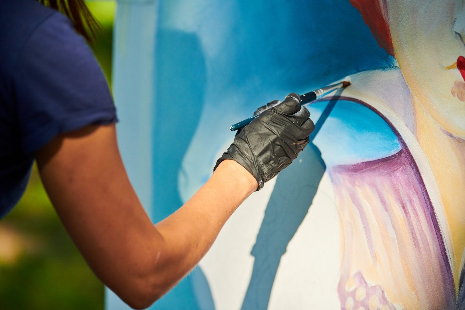 Girl artist hand holds paint brush and draws surreal fairy tale portrait on white canvas outdoor art painting festival, paintings art picture process. Woman artist paints atmospheric surreal picture