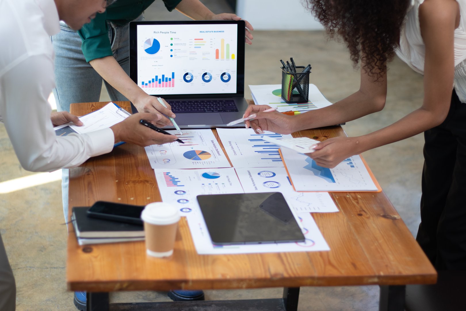 A team of Asian businessmen analyzes the proposed sales market segments. Trading experts use data charts on paper in the office lobby.