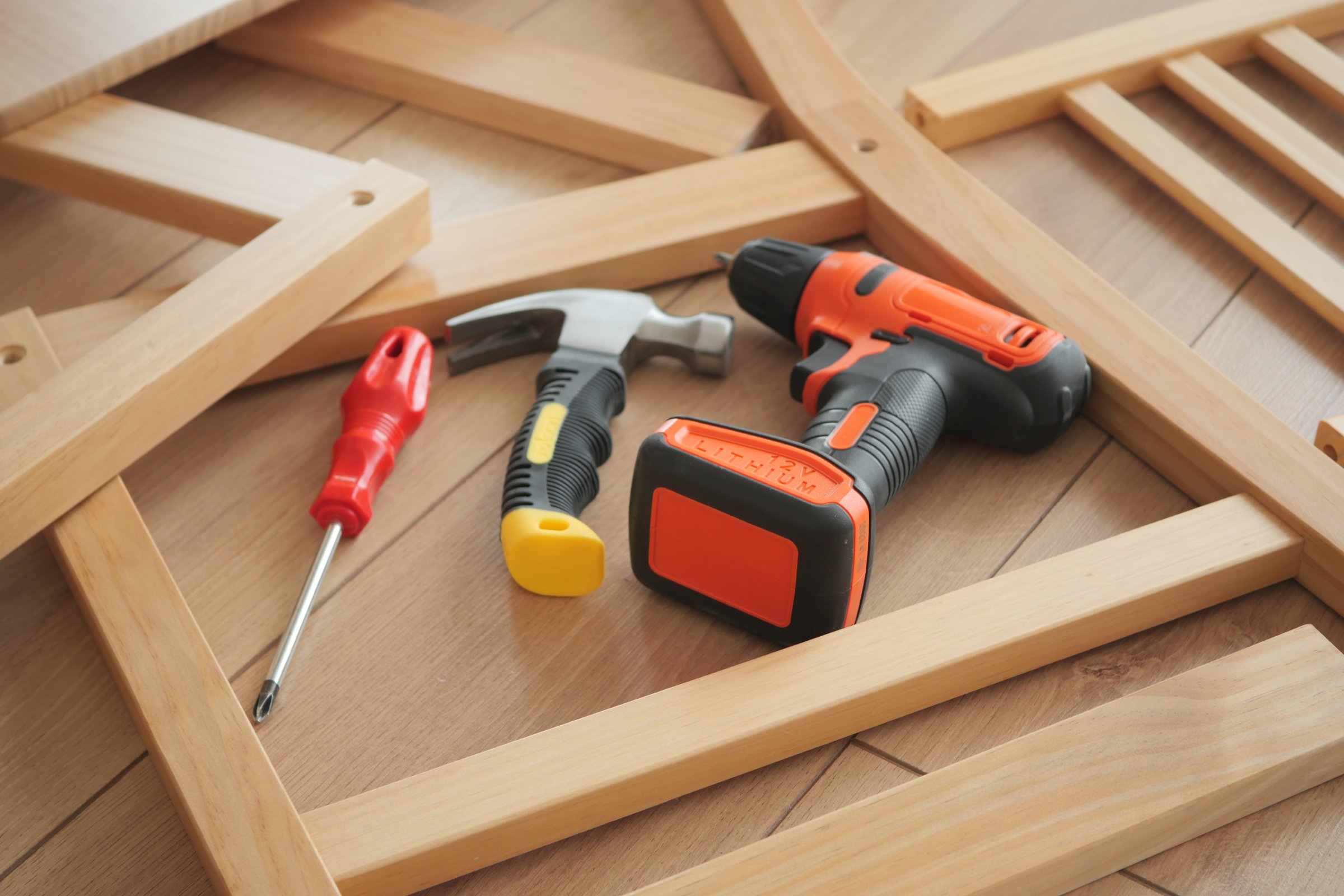 Various tools are laid out for assembling furniture on a wooden surface.