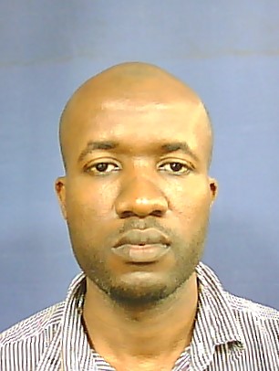 Portrait of a person with a neutral expression against a blue background, wearing a striped shirt.