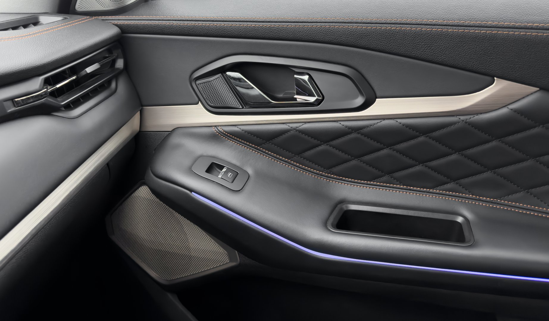 Door handle with power window control buttons. Black perforated leather interior with stitching. Modern car black leather interior details.