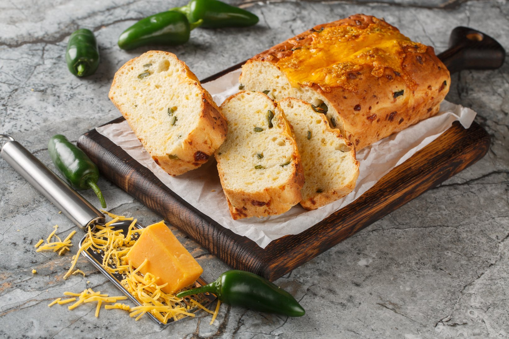 Jalapeno Cheddar Bread is perfectly crusty on the outside, with a soft fluffy inside closeup on the wooden board on the table. Horizontal