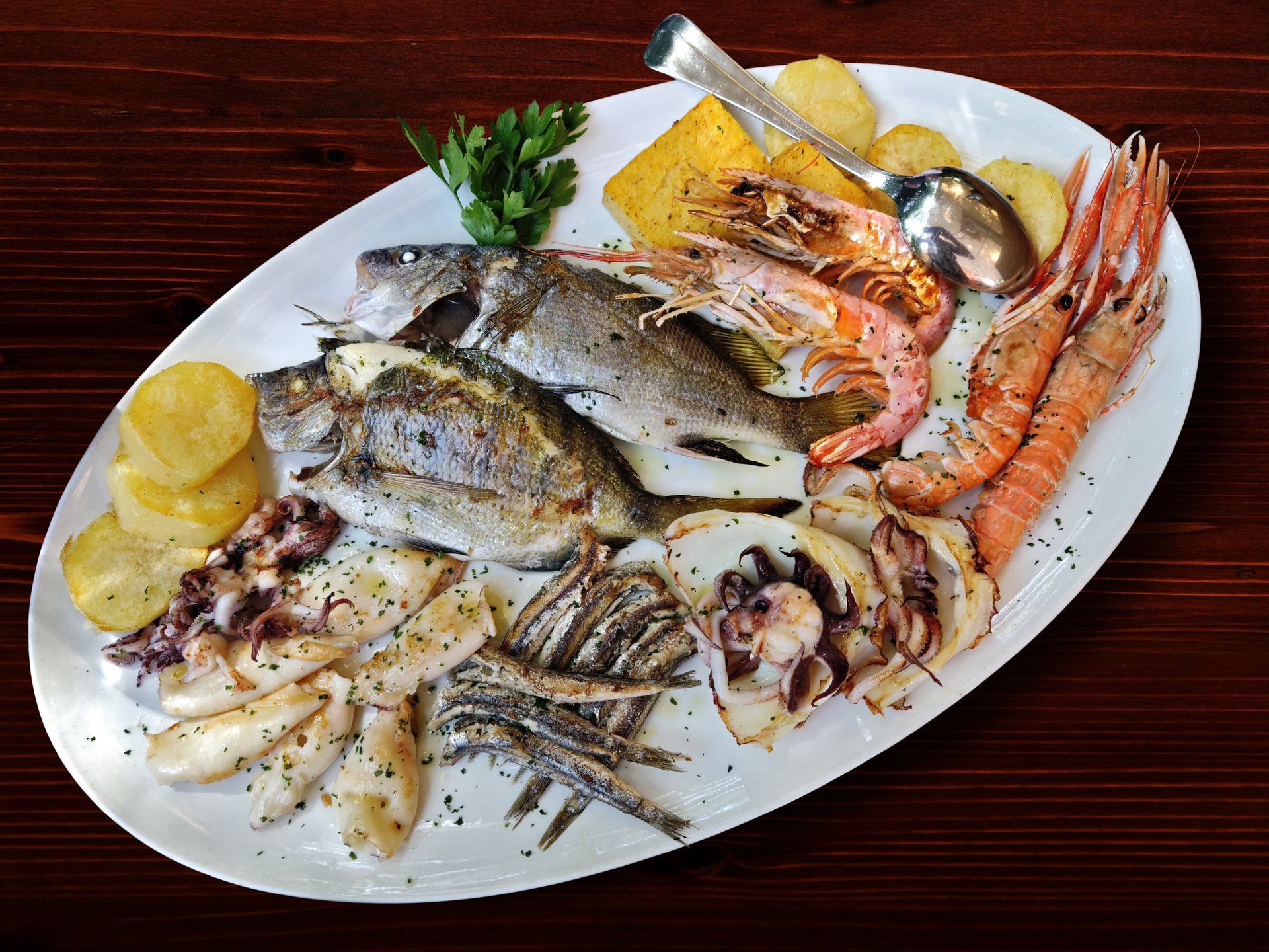Tray with mixed grilled fish on wooden background