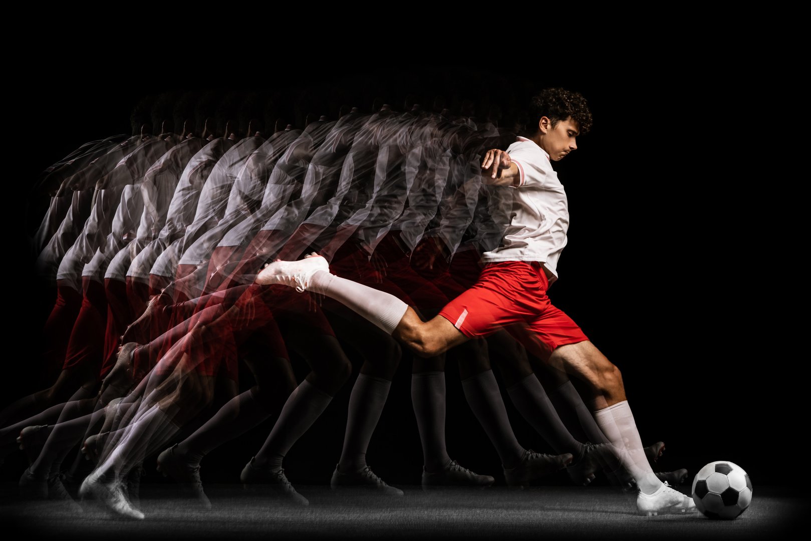Scoring goals. Young professional goalkeeper playing football isolated on black background.. Sport achievement. Concept of action, speed, energy, sport, competition and ad.