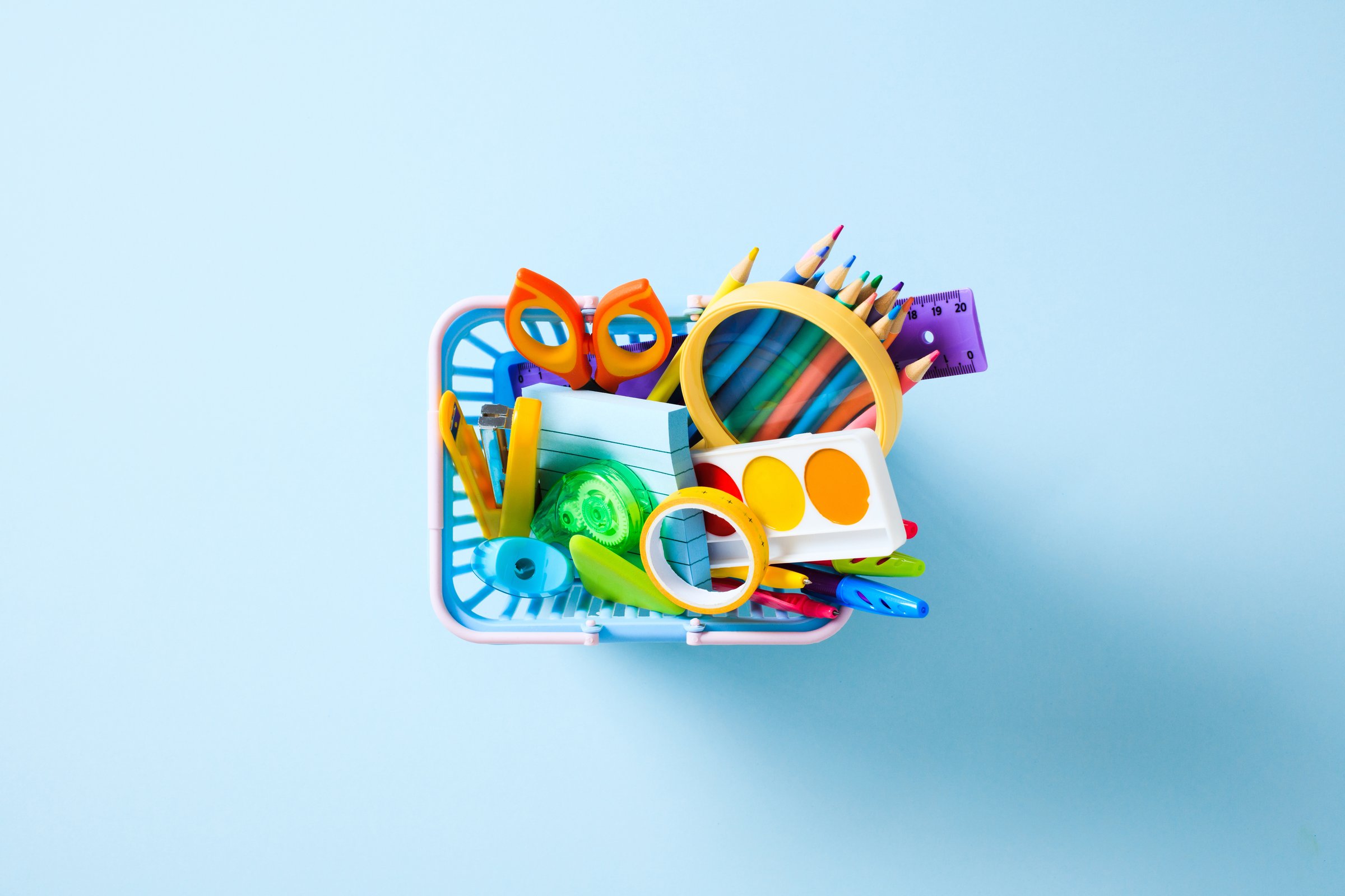 Flat Lay of school supplies. A basket containing children's creative tools for drawing and learning.