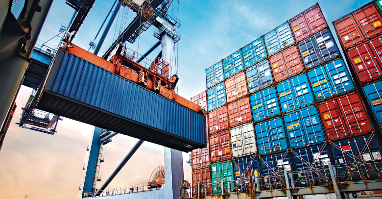 Shipping containers being loaded onto a cargo ship at a dockyard, with cranes and a blue sky in the background.