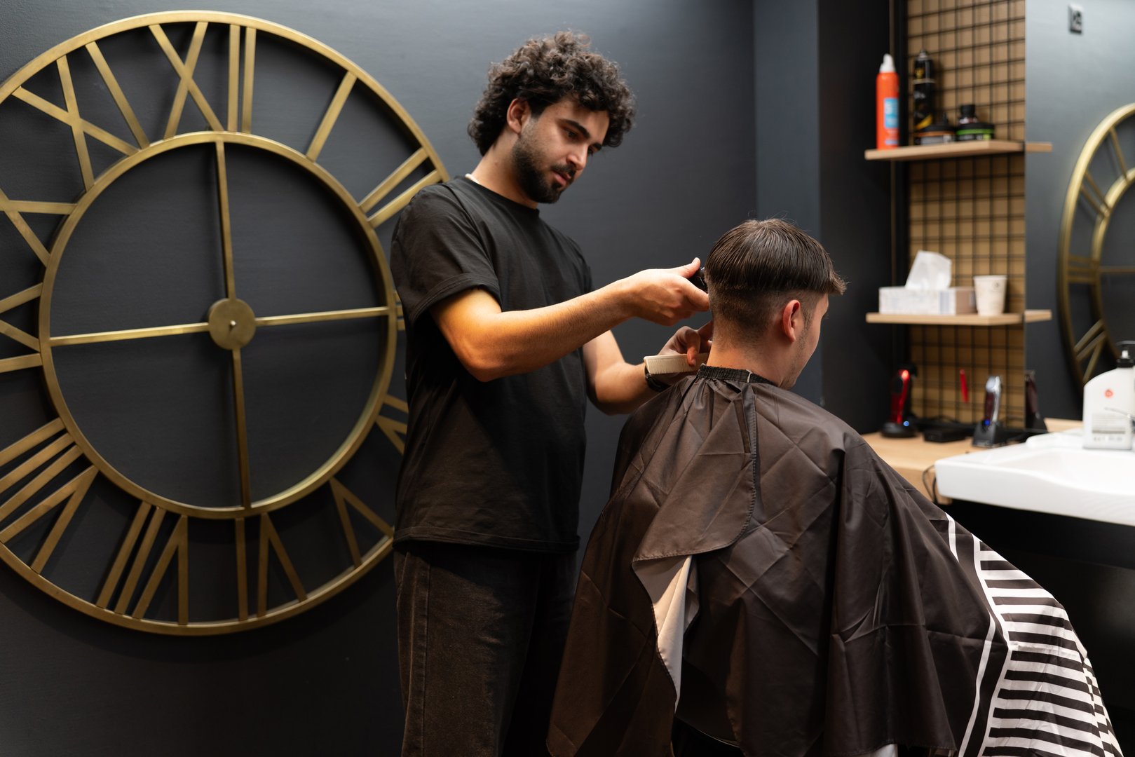 Barber using hair clipper on client's neck in modern barbershop