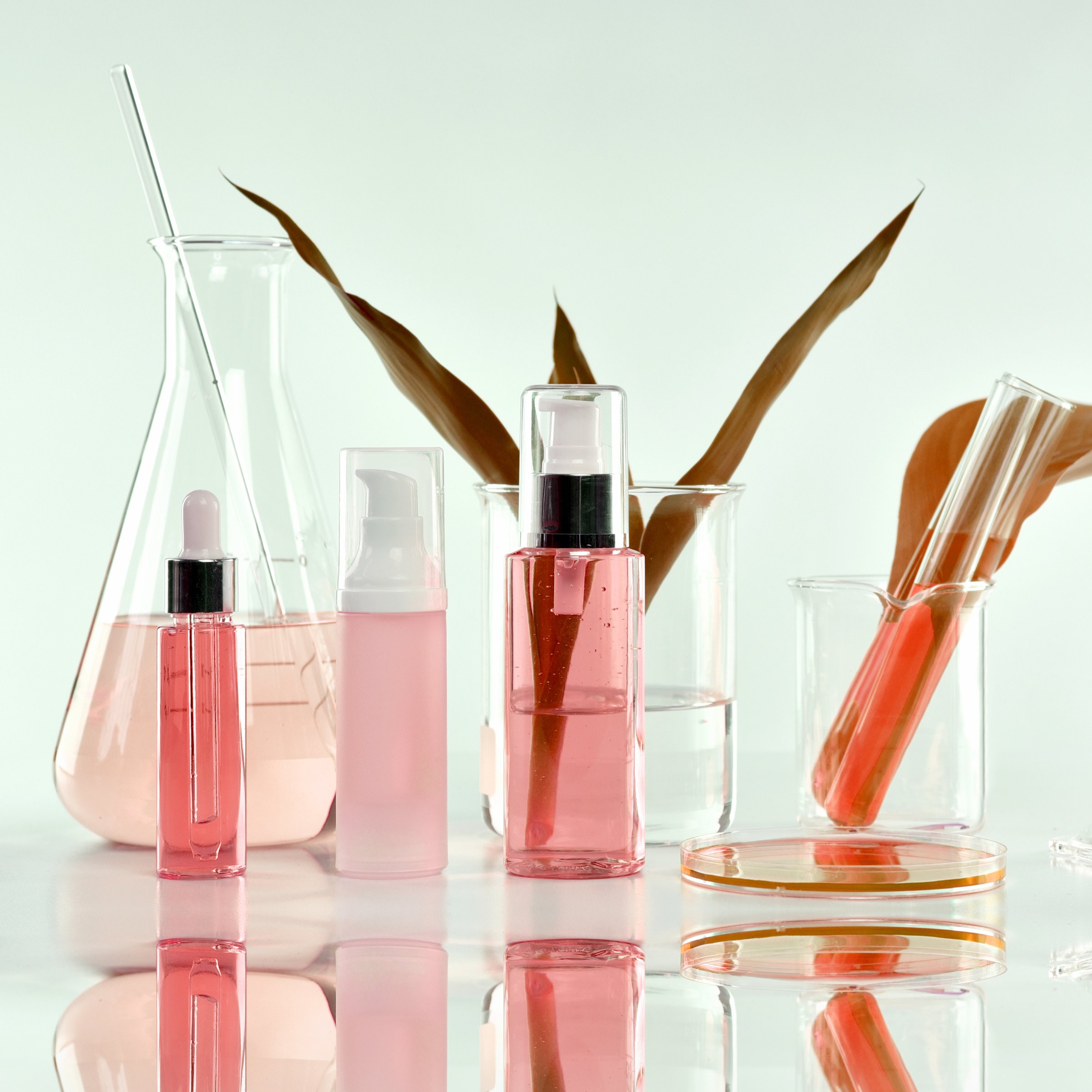 Cosmetic bottle containers with green herbal leaves and scientific glassware, Blank label package for branding mock-up, Research and develop natural organic beauty skincare product concept.