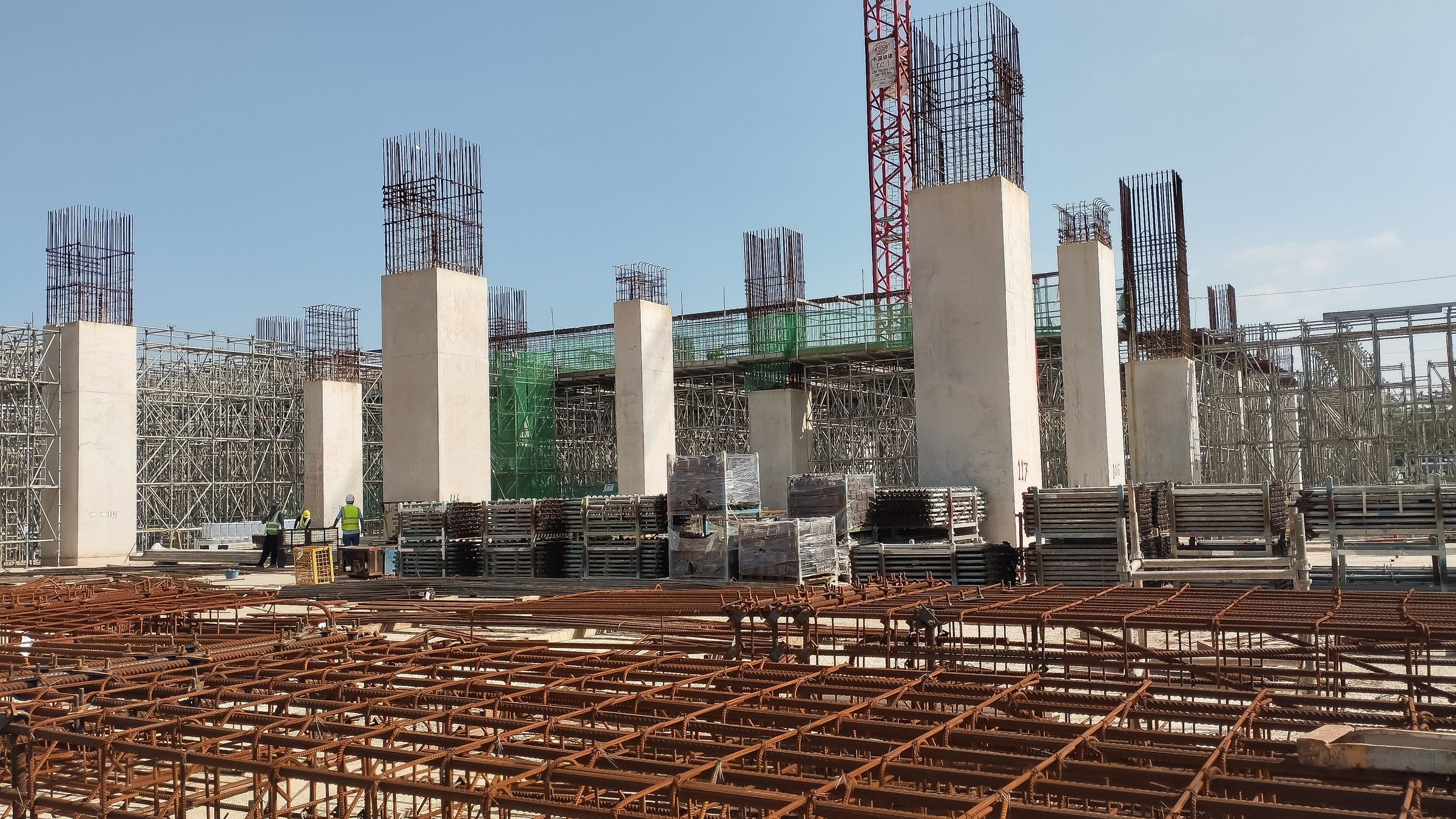 construction site with tower crane and reinforced concrete columns on-going construction
