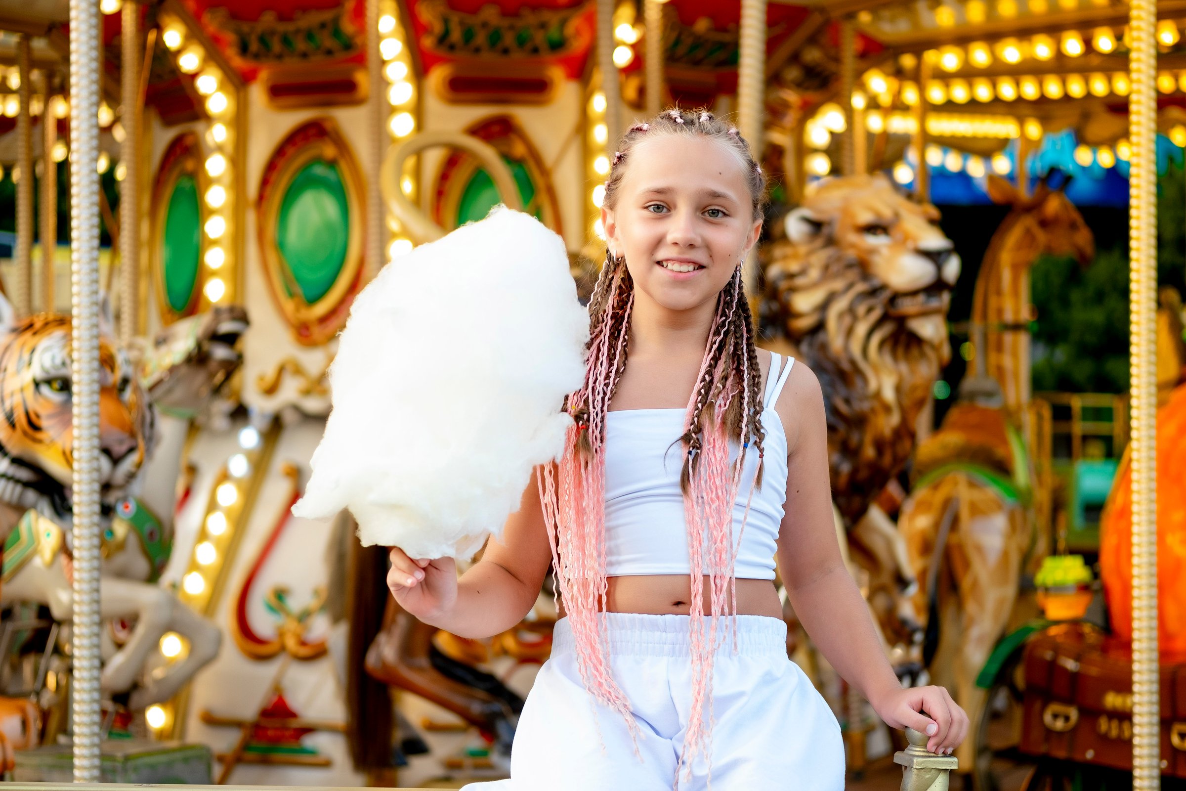 a child in an amusement and amusement park, a happy girl eating cotton candy and enjoying the holidays and summer, a child came to ride on a carousel.