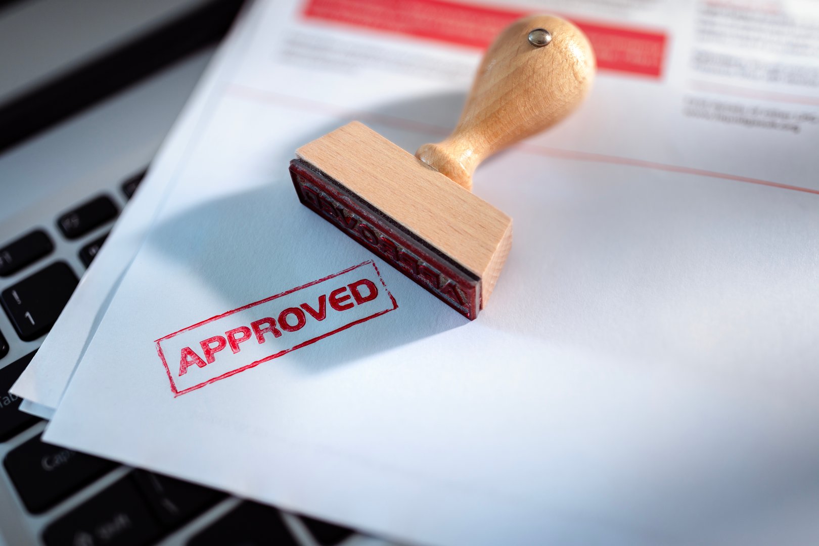 Approved stamp on application form or business agreement document on laptop in office