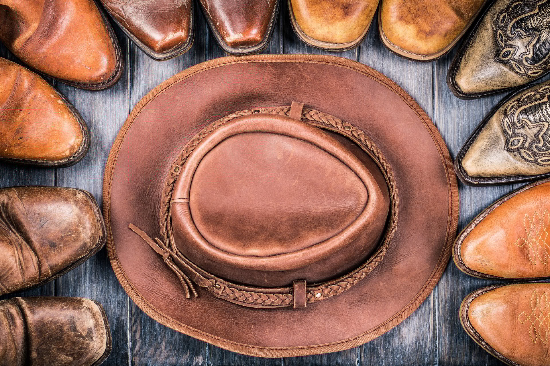 Wild West retro cowboy hat and old leather boots on wooden floor. Vintage style filtered photo