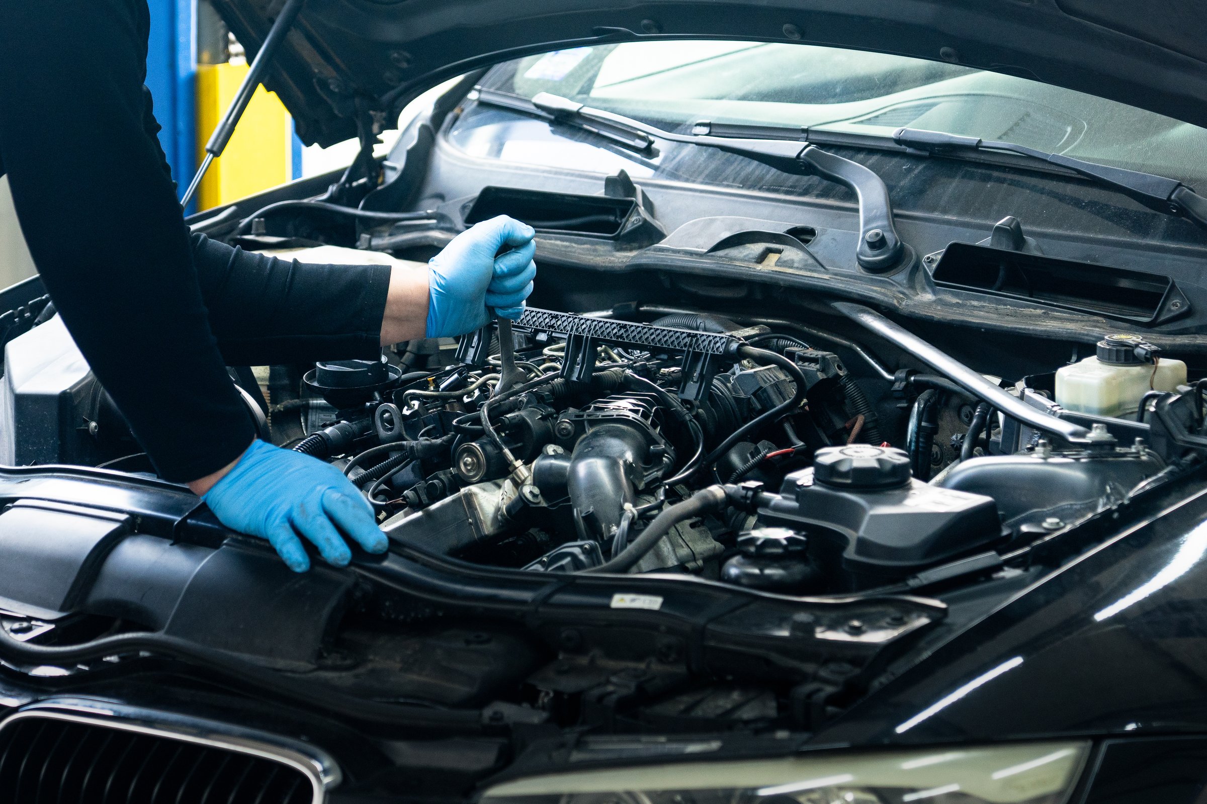 Close up of male hands next to car engine. Serviceman repair car in car service