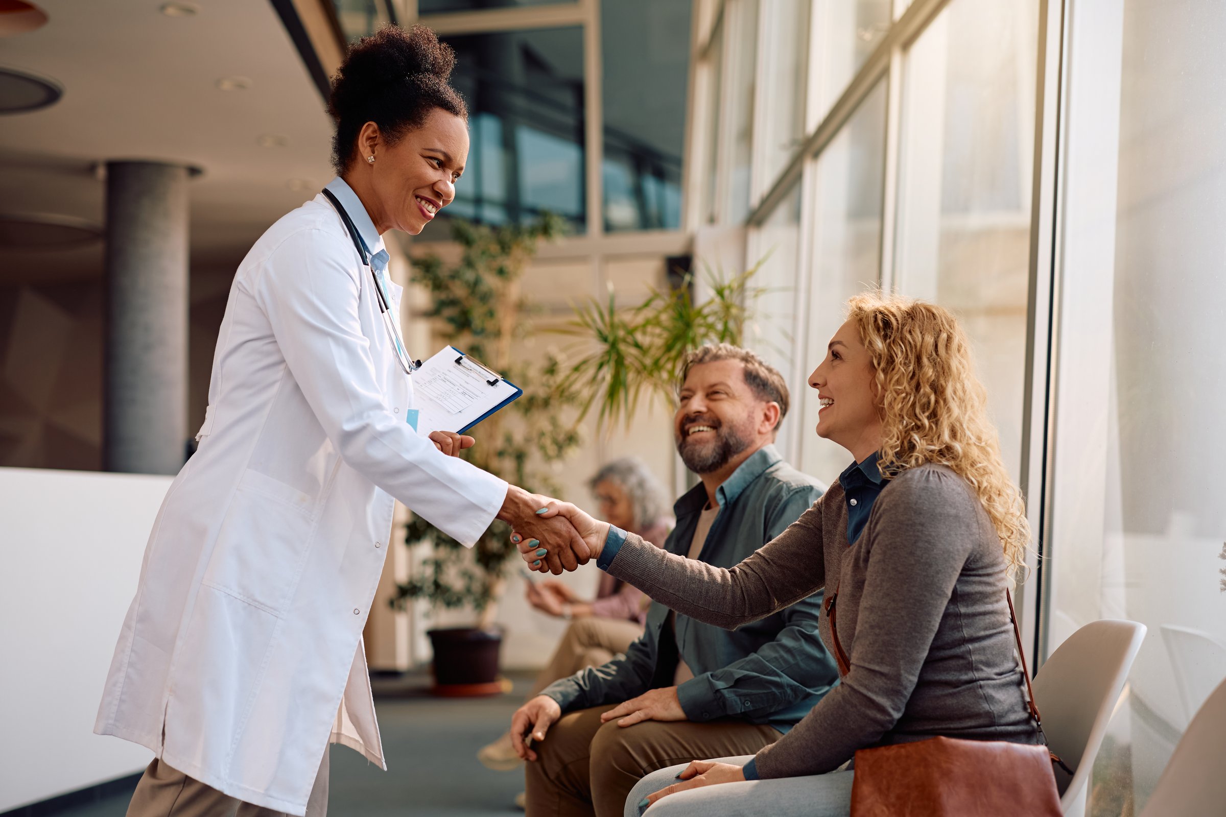 Happy African American doctor greeting her patients at medical clinic.