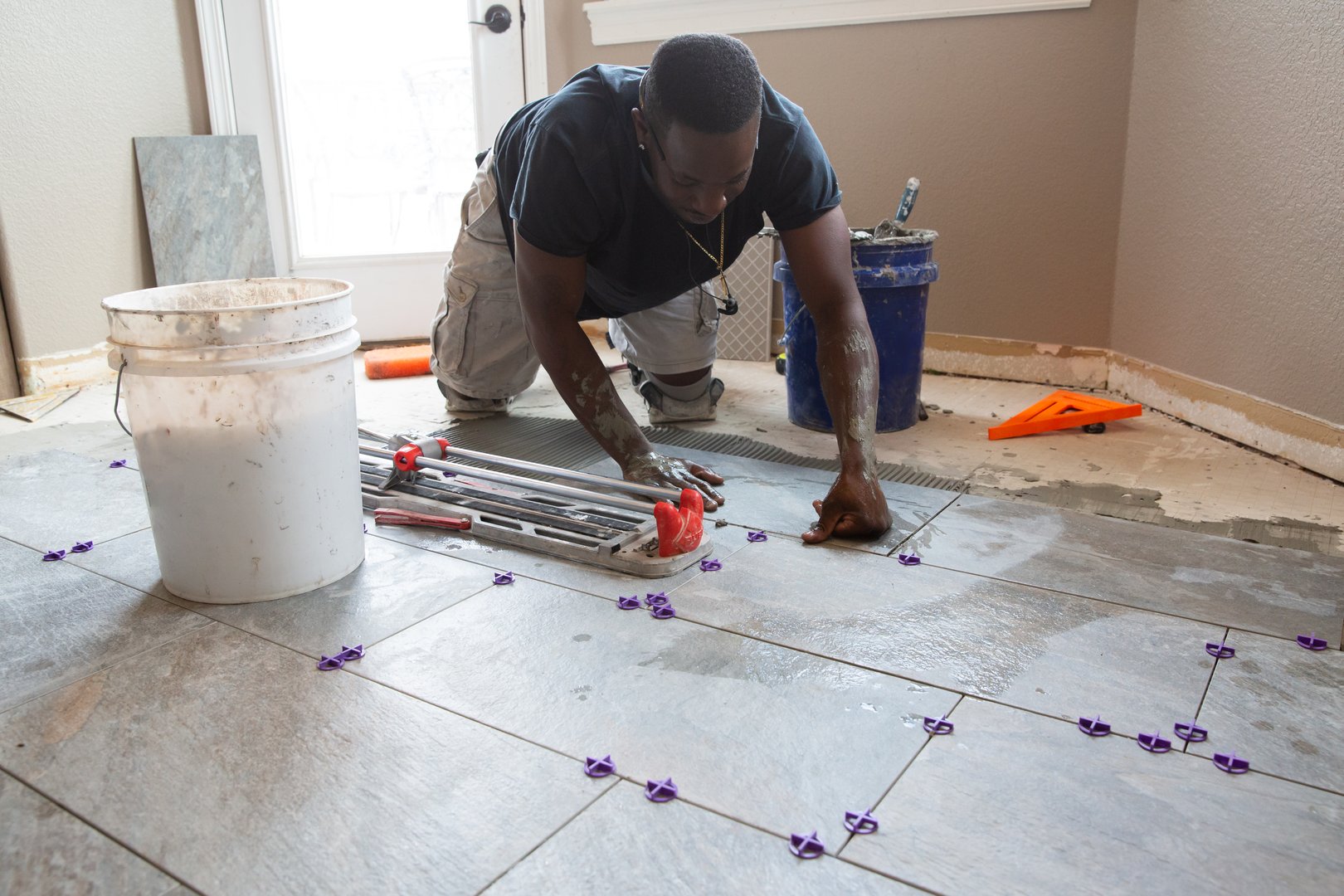 One man installing tile in a kitchen remodel.